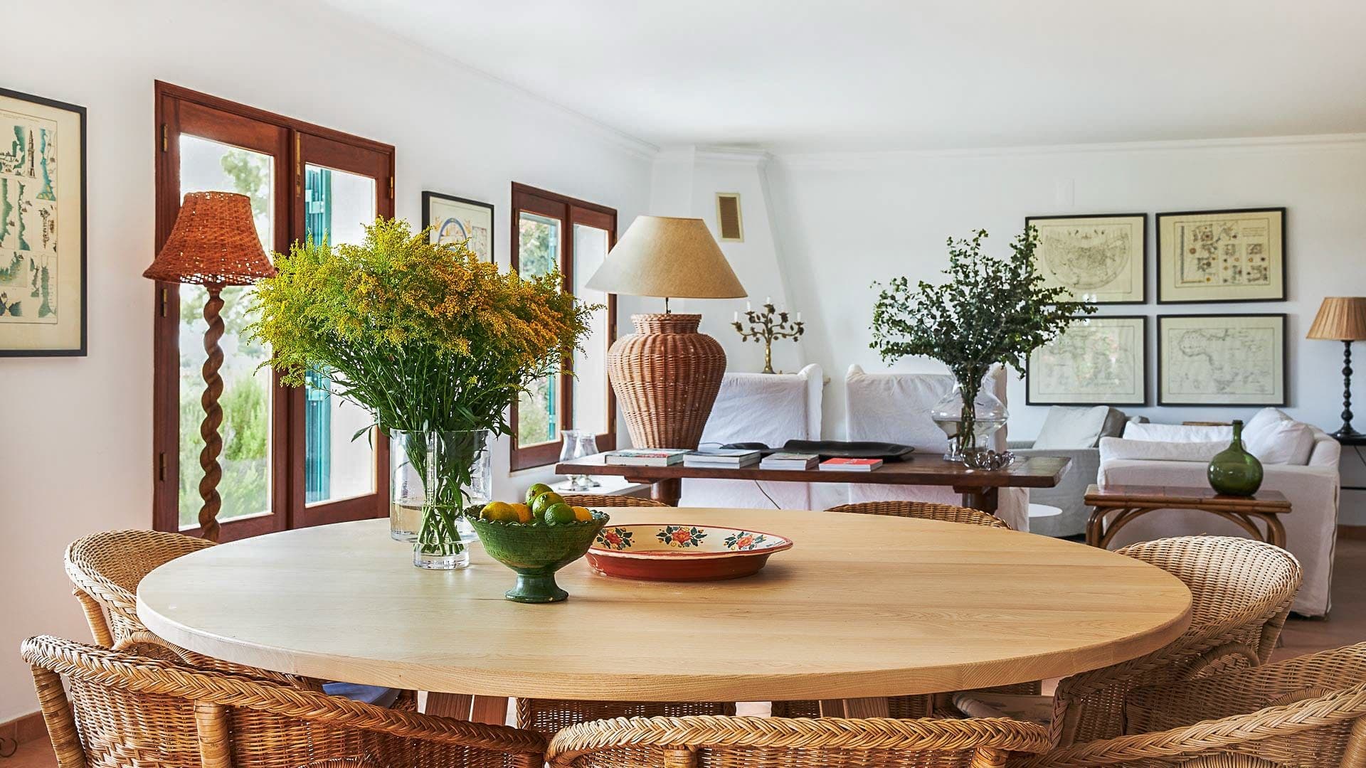 Round wooden dining table beside a linen sofa in the open-plan living room