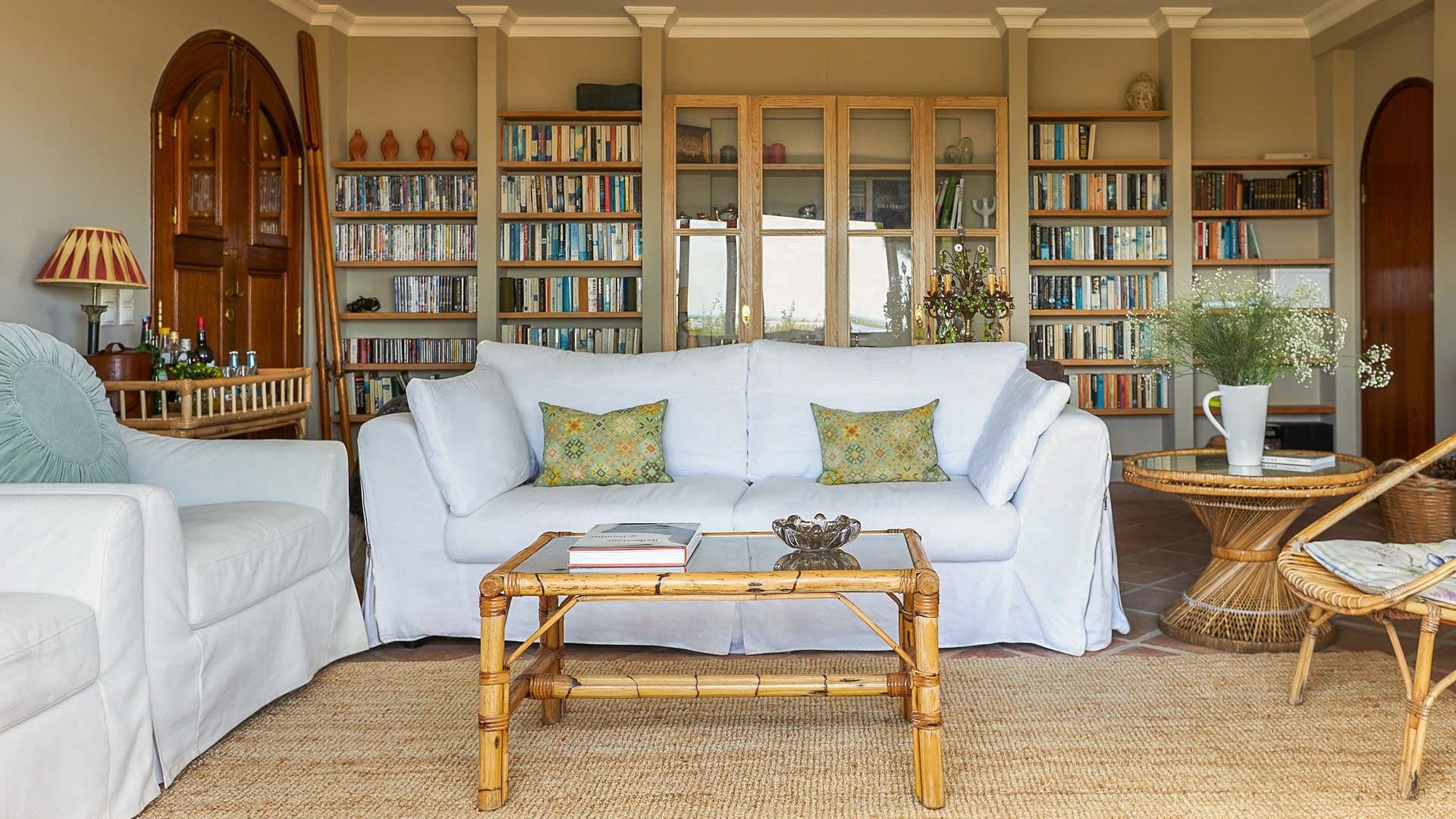 Book-lined lounge with a white slipcovered sofa and bamboo coffee table