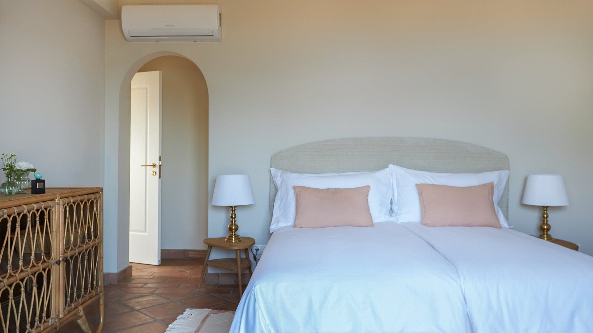 Bedroom with a rattan headboard and soft pink and blue linens