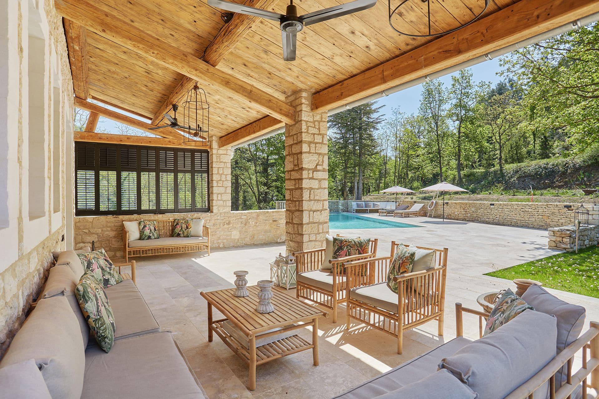 Covered outdoor lounge with timber ceiling and bamboo seating overlooking the pool at A Glass of Champagne, Provence