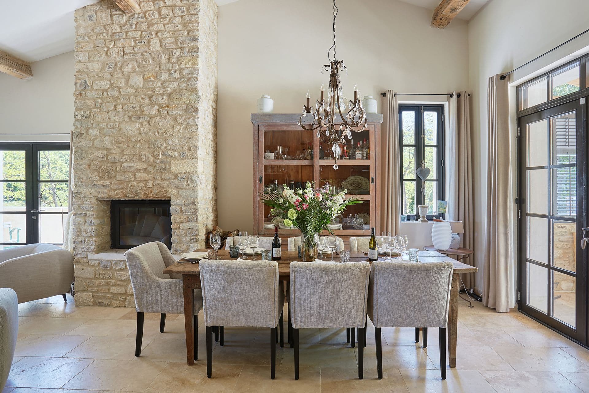 Oak dining table for eight beside a stone fireplace and glazed dresser at A Glass of Champagne, Provence