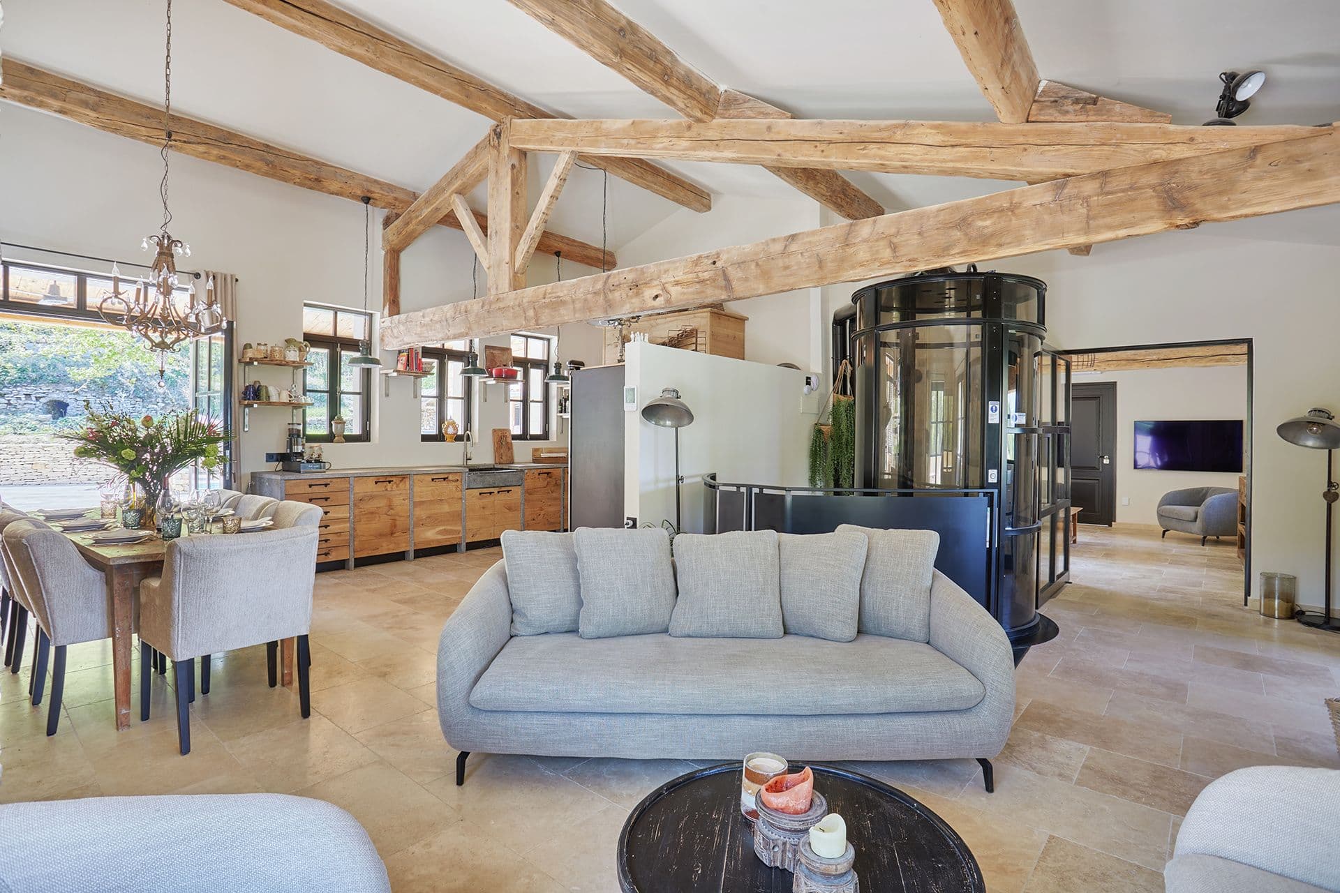 Open-plan living, dining and kitchen space with exposed beams and a glass lift at A Glass of Champagne, Provence