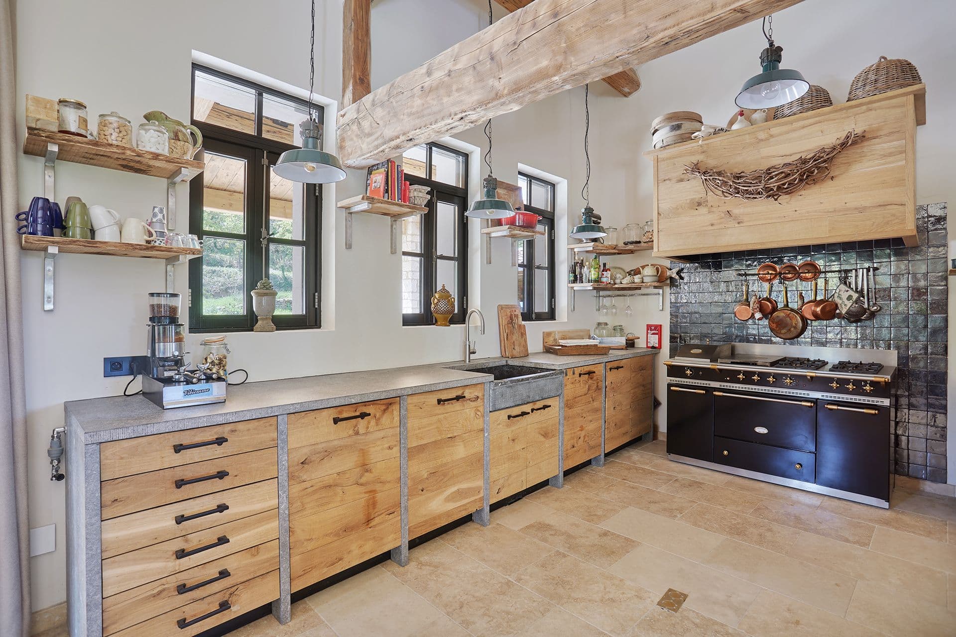 Farmhouse kitchen with reclaimed-oak units, stone worktops, a black range cooker and copper pans at A Glass of Champagne, Provence