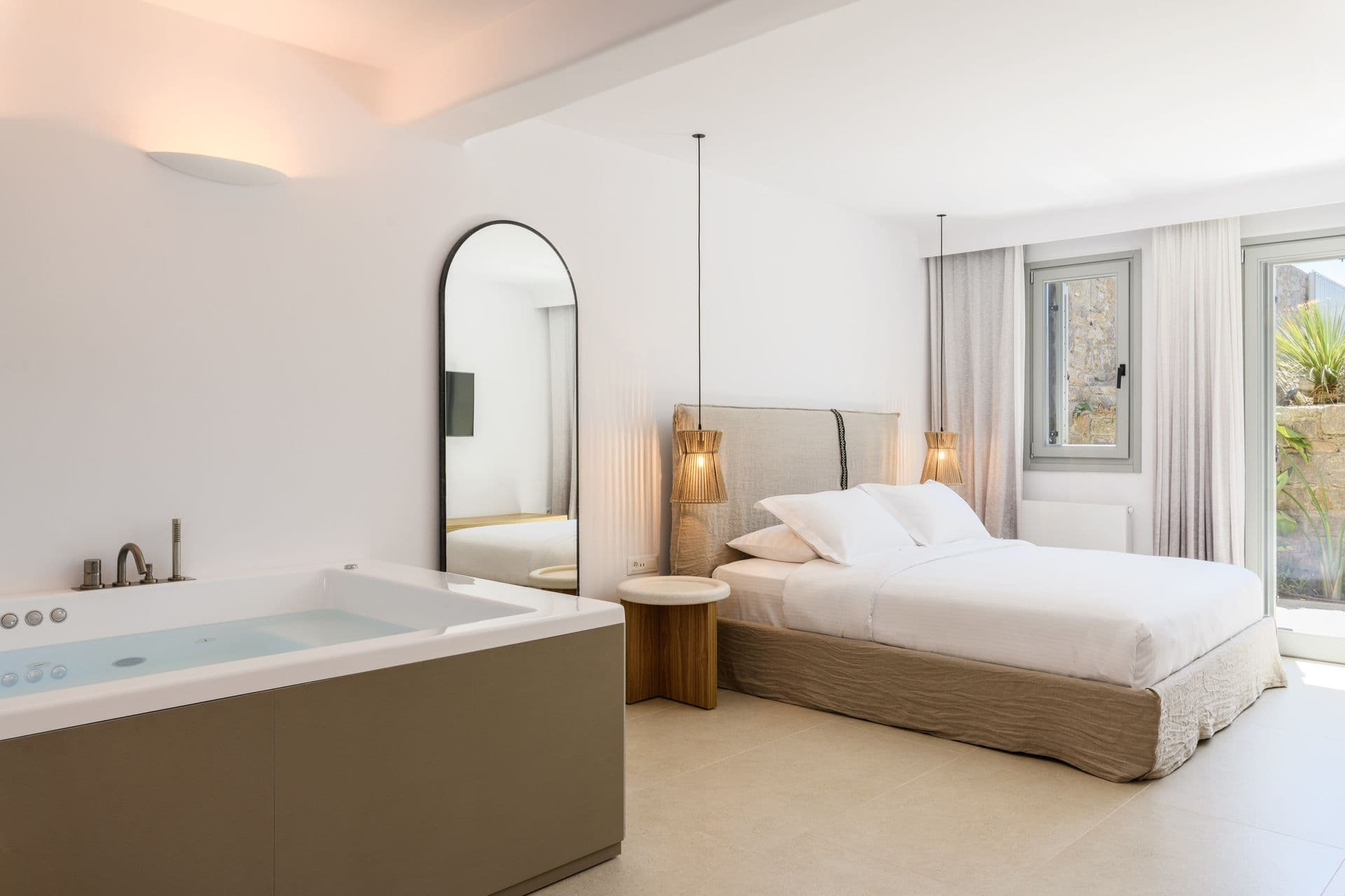 Double bedroom with an arched mirror and a sitting area at Cycladic Sunset Stay, Mykonos