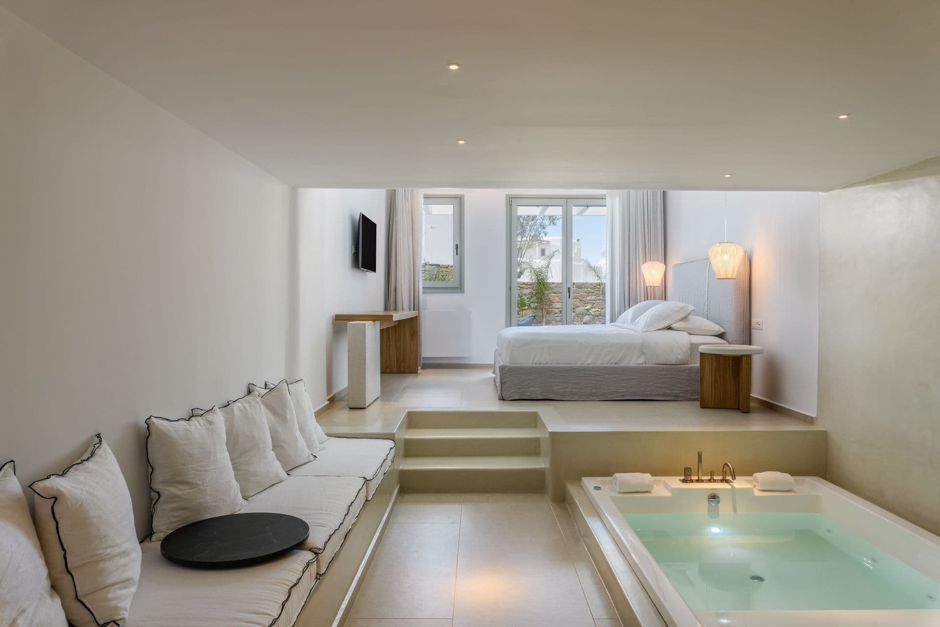 Bedroom suite with a sunken jacuzzi and sitting area at Cycladic Sunset Stay, Mykonos