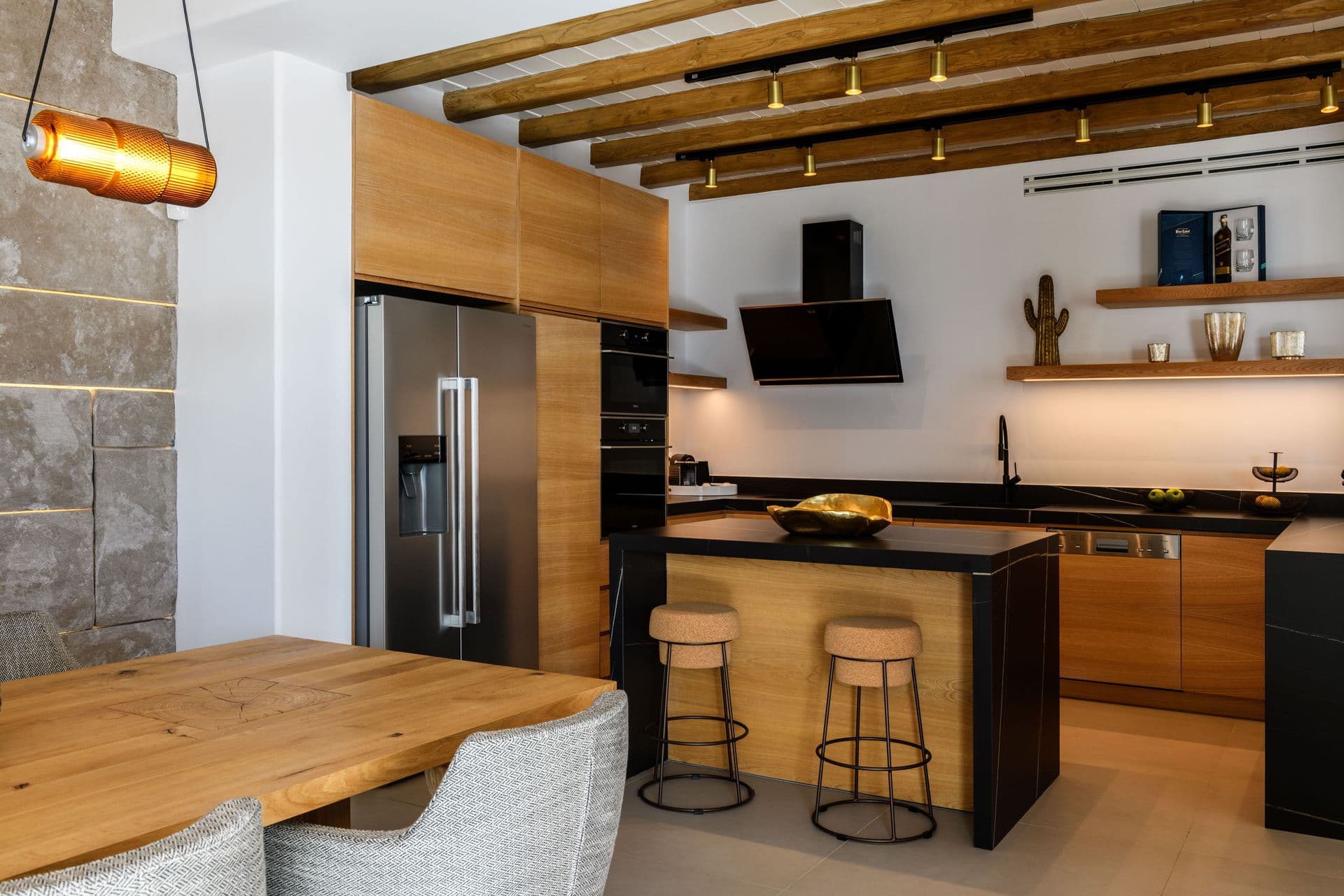 Oak kitchen with a black stone island and bar stools at Cycladic Sunset Stay, Mykonos