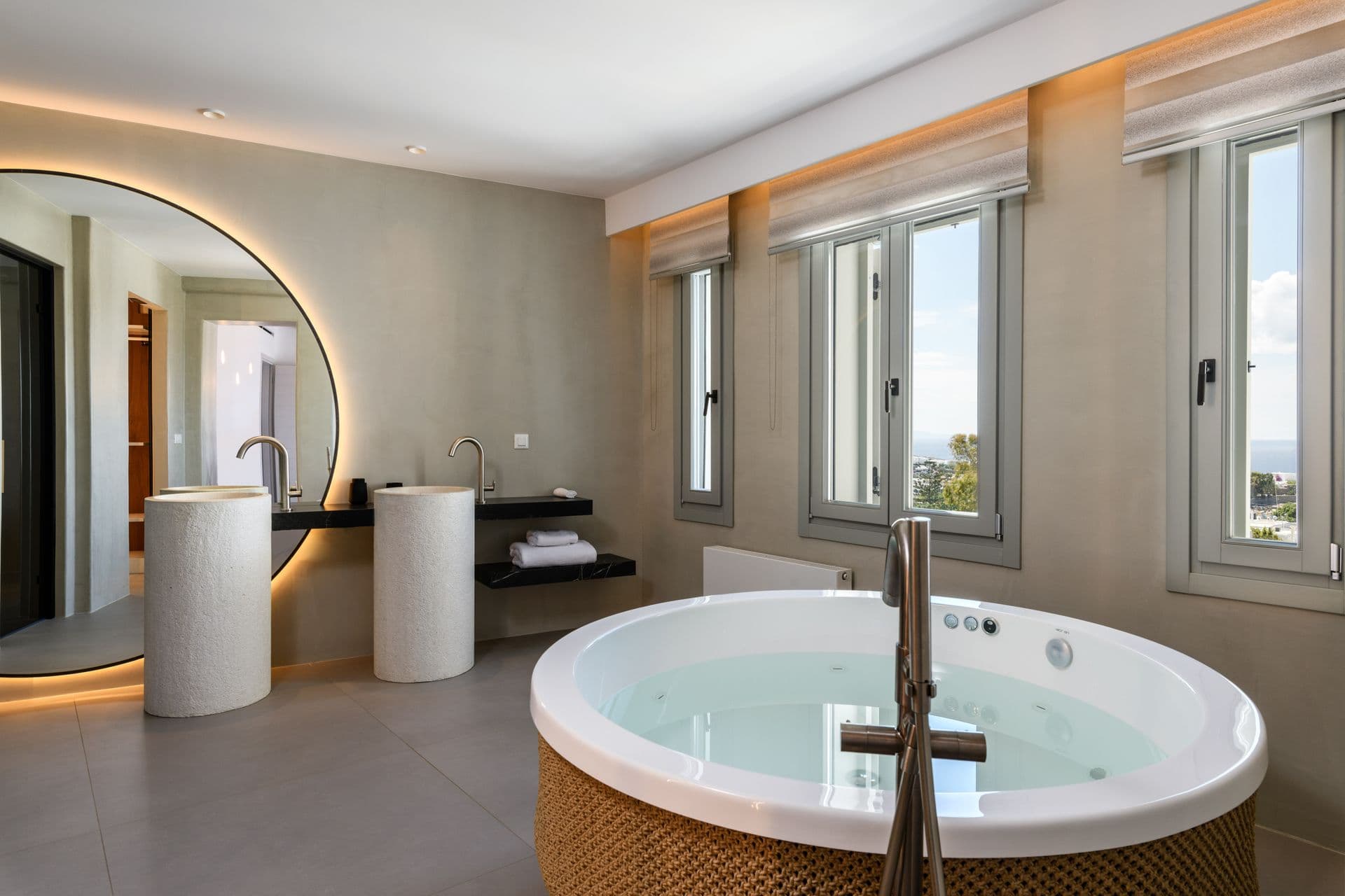 Bedroom suite with a round jacuzzi and twin vanity at Cycladic Sunset Stay, Mykonos