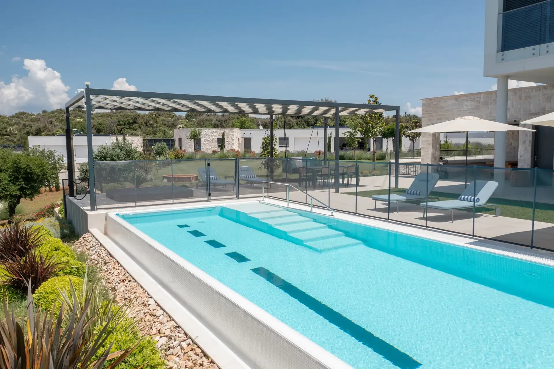 Poolside pergola and sun loungers at Highland Avenue, framed by manicured lawns.