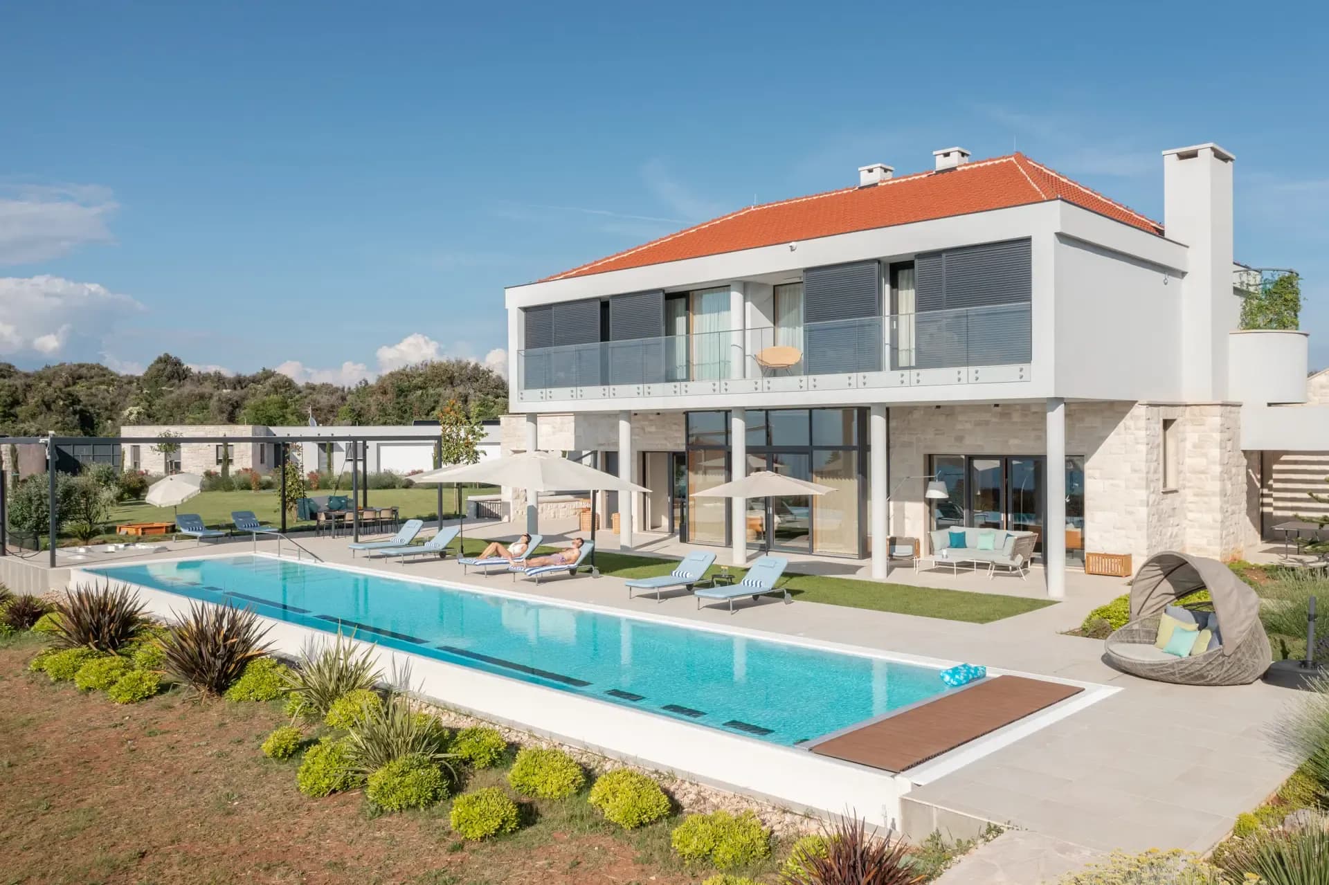 Highland Avenue's modern villa and pool viewed from the lawn, with hills beyond.