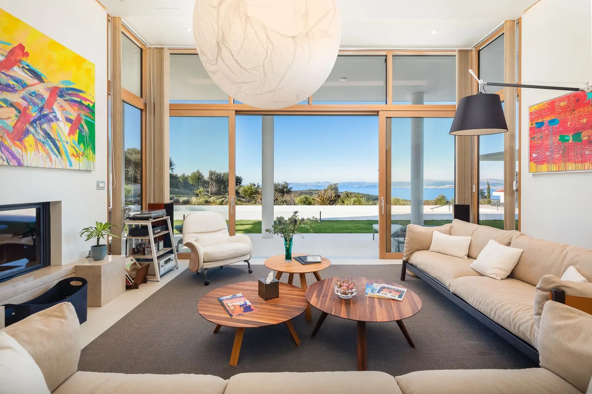Living room at Highland Avenue with round wood coffee tables, linen sofas and bold abstract art.