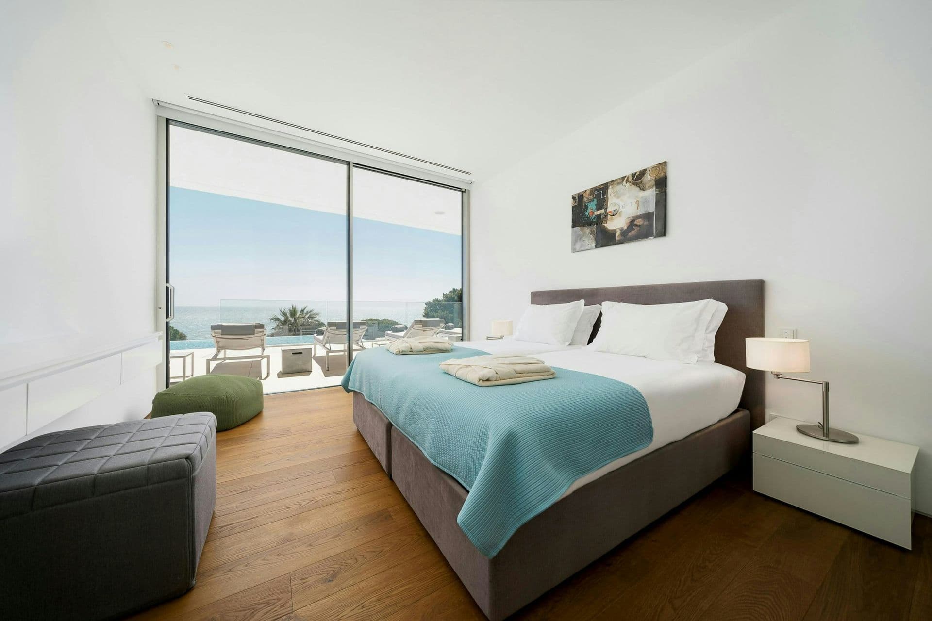 Bedroom with aqua accents opening to a sea-view terrace at A Coastal Crown, Lagos