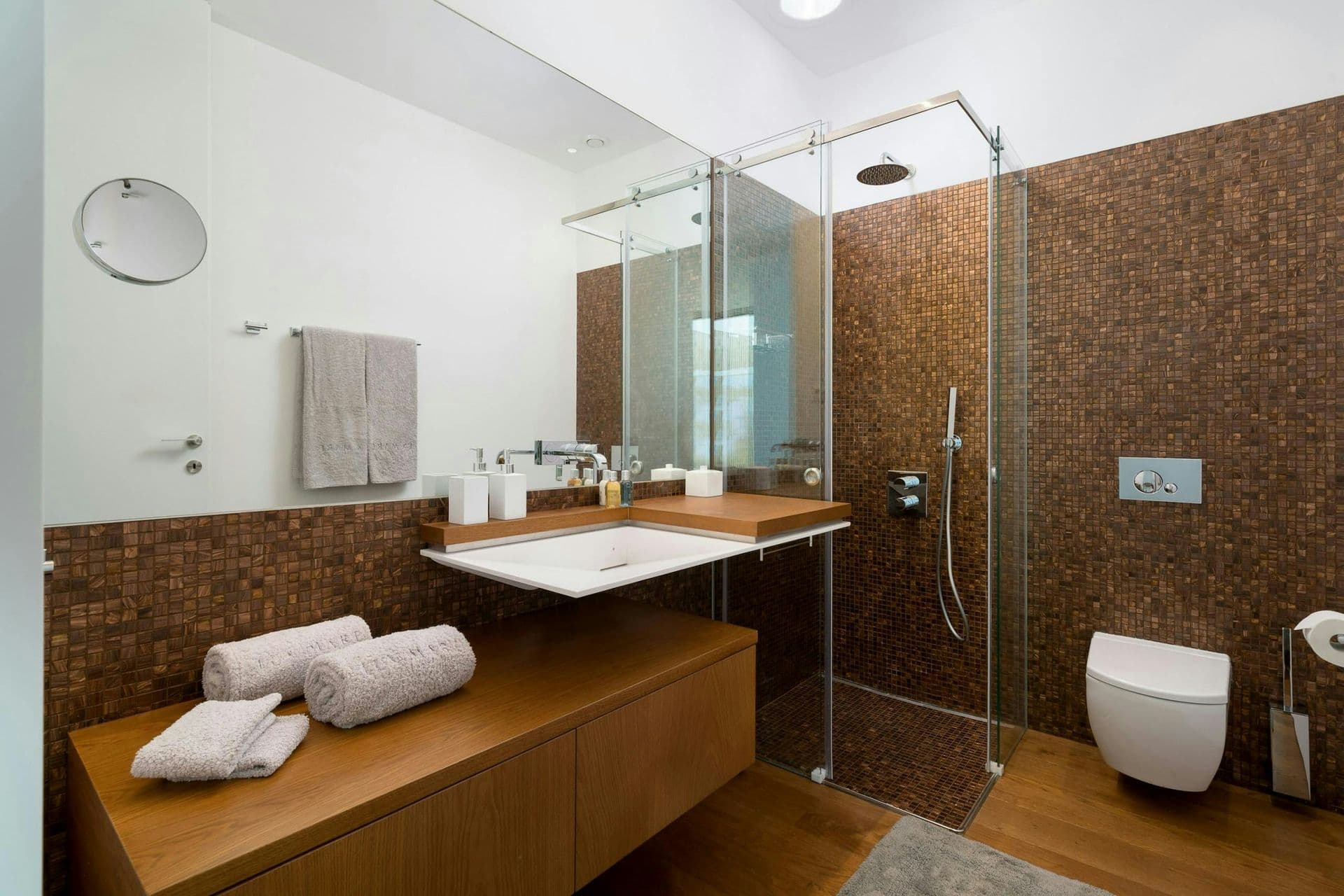 Walk-in shower in earth-toned mosaic at A Coastal Crown, Lagos