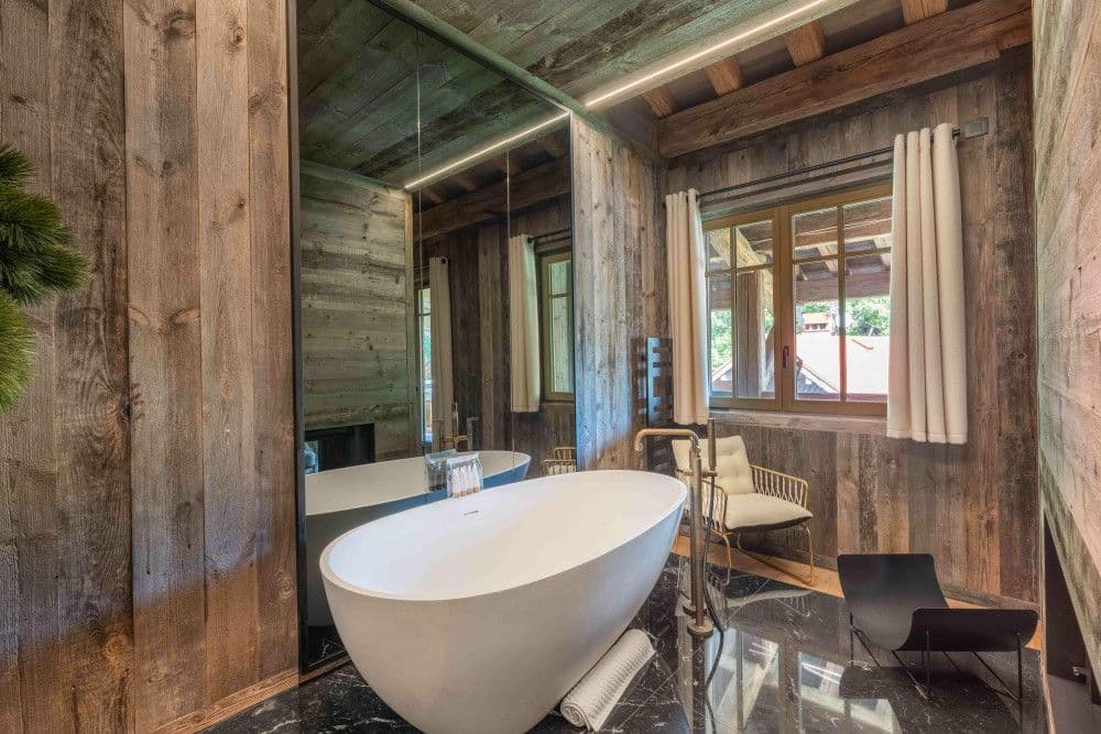 Bathroom with a freestanding bath against a timber wall at Megeve Centre 7