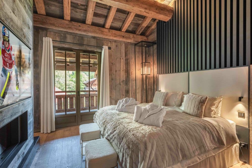 Master bedroom with fur throws and a mountain-view balcony at Megeve Centre 7