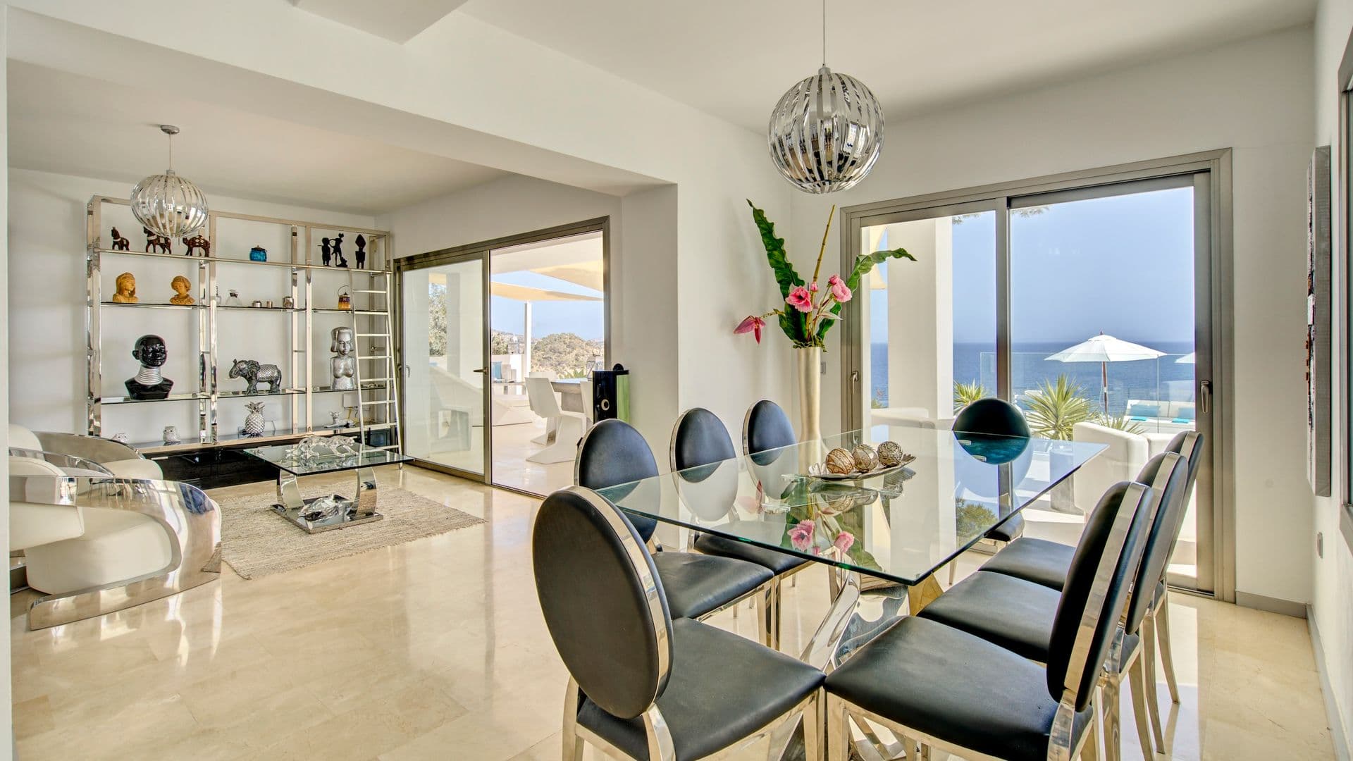 Dining area with a glass table, black chairs and sea view