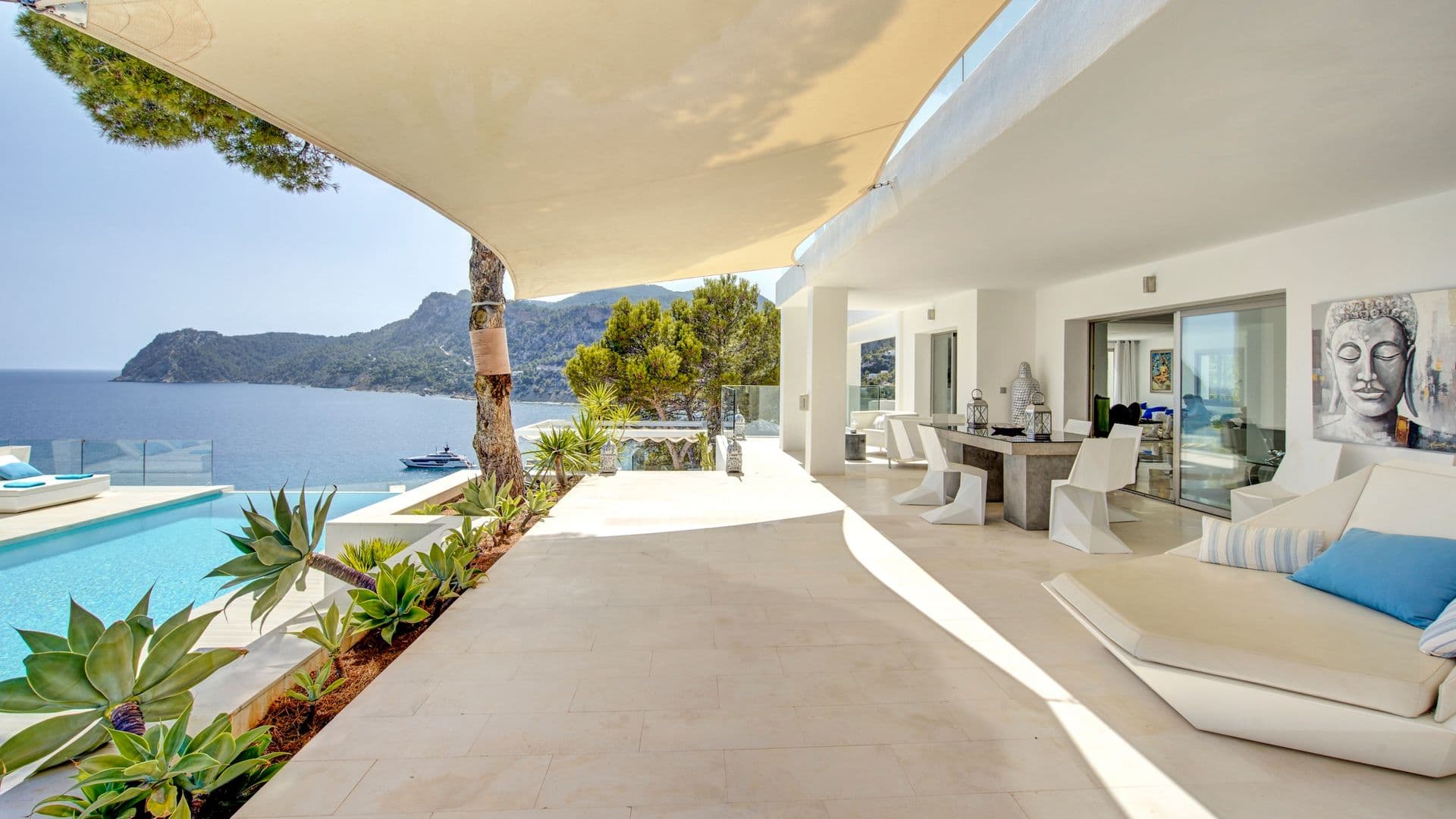 Shaded terrace with lounge seating and dining area overlooking the sea