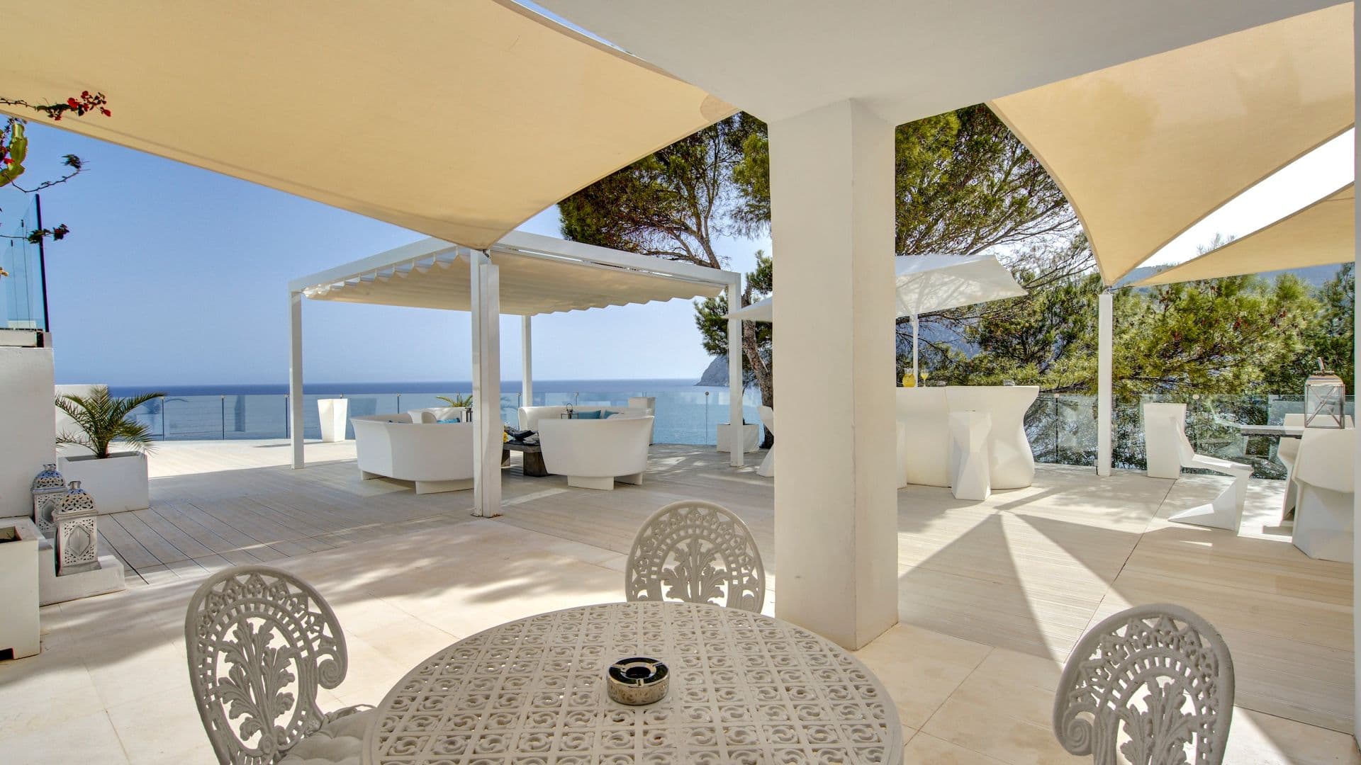 Outdoor dining table beneath a pergola with sea views