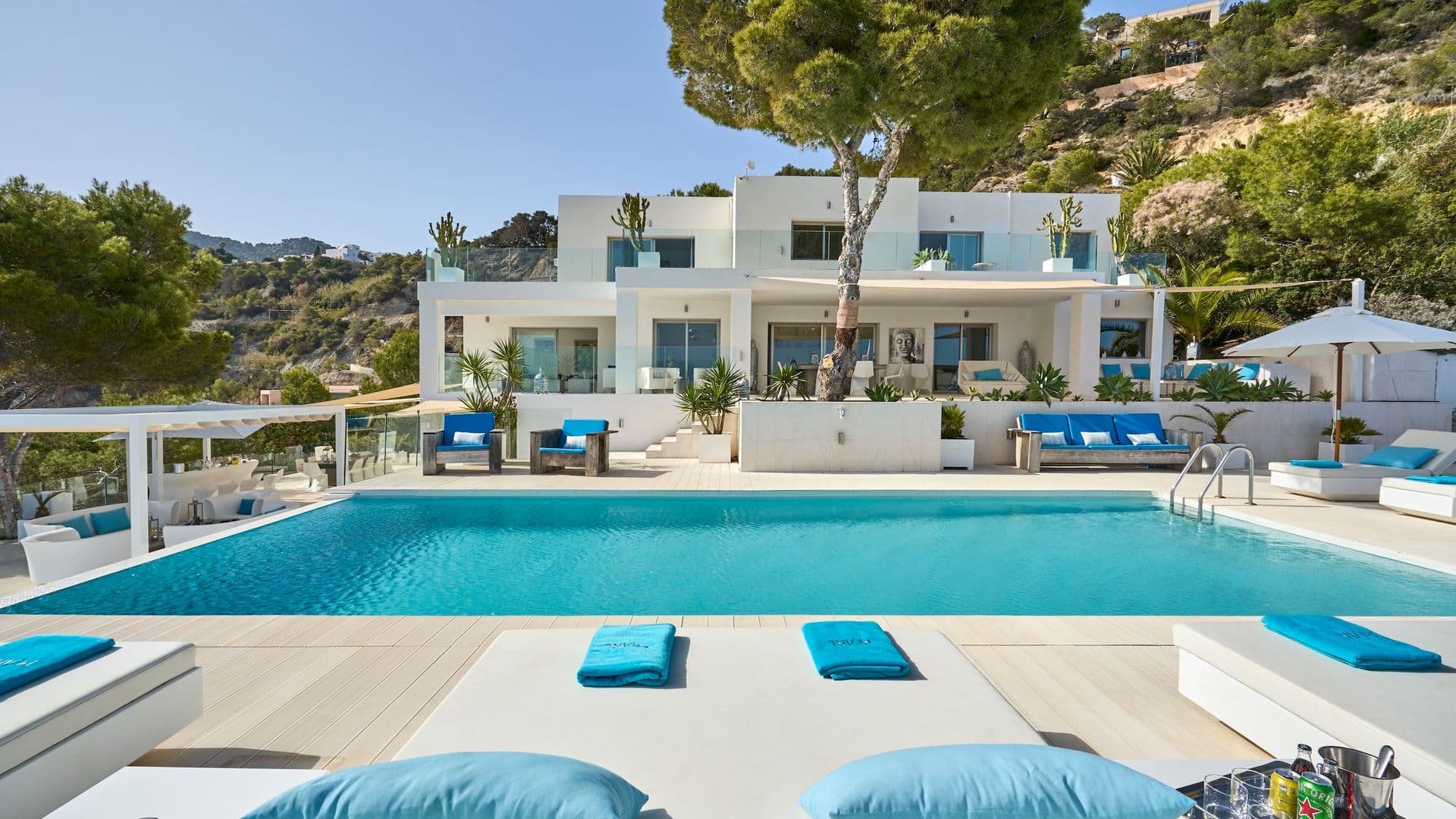 Whitewashed Ibiza style villa with a long pool and blue sun loungers