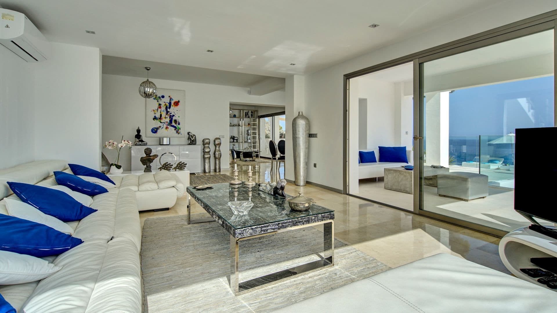 White lounge with blue cushions and curated sculptural decor