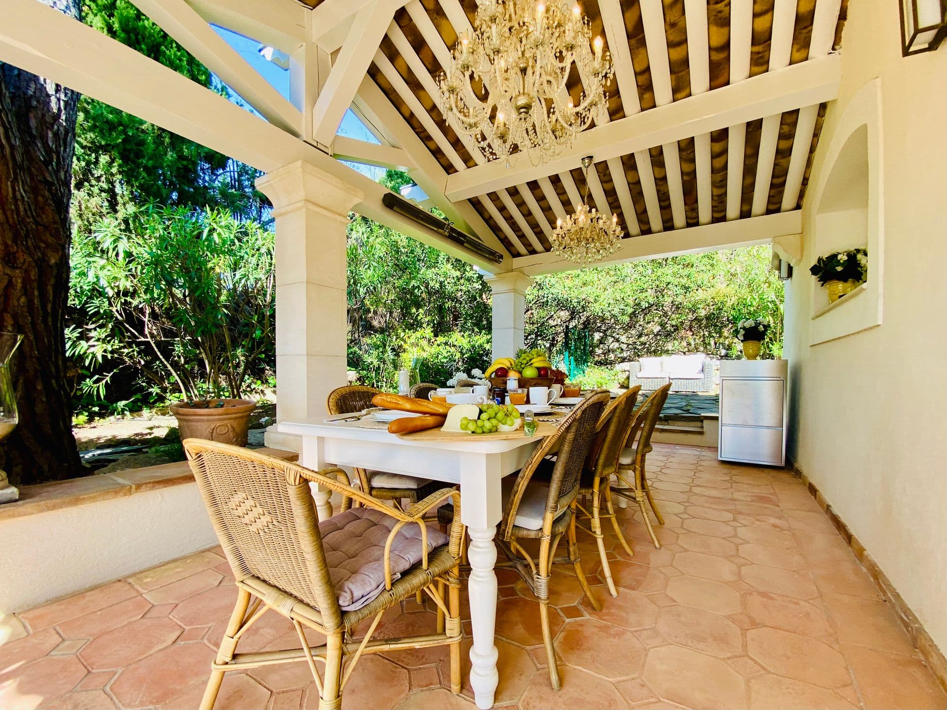 Covered stone loggia with dining table looking onto the garden.