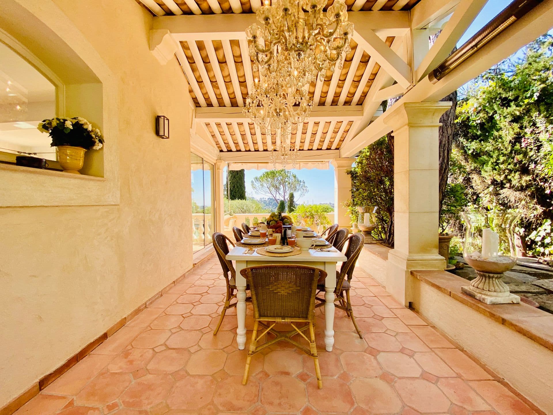 Terrace dining area with a wrought-iron chandelier and beamed ceiling.