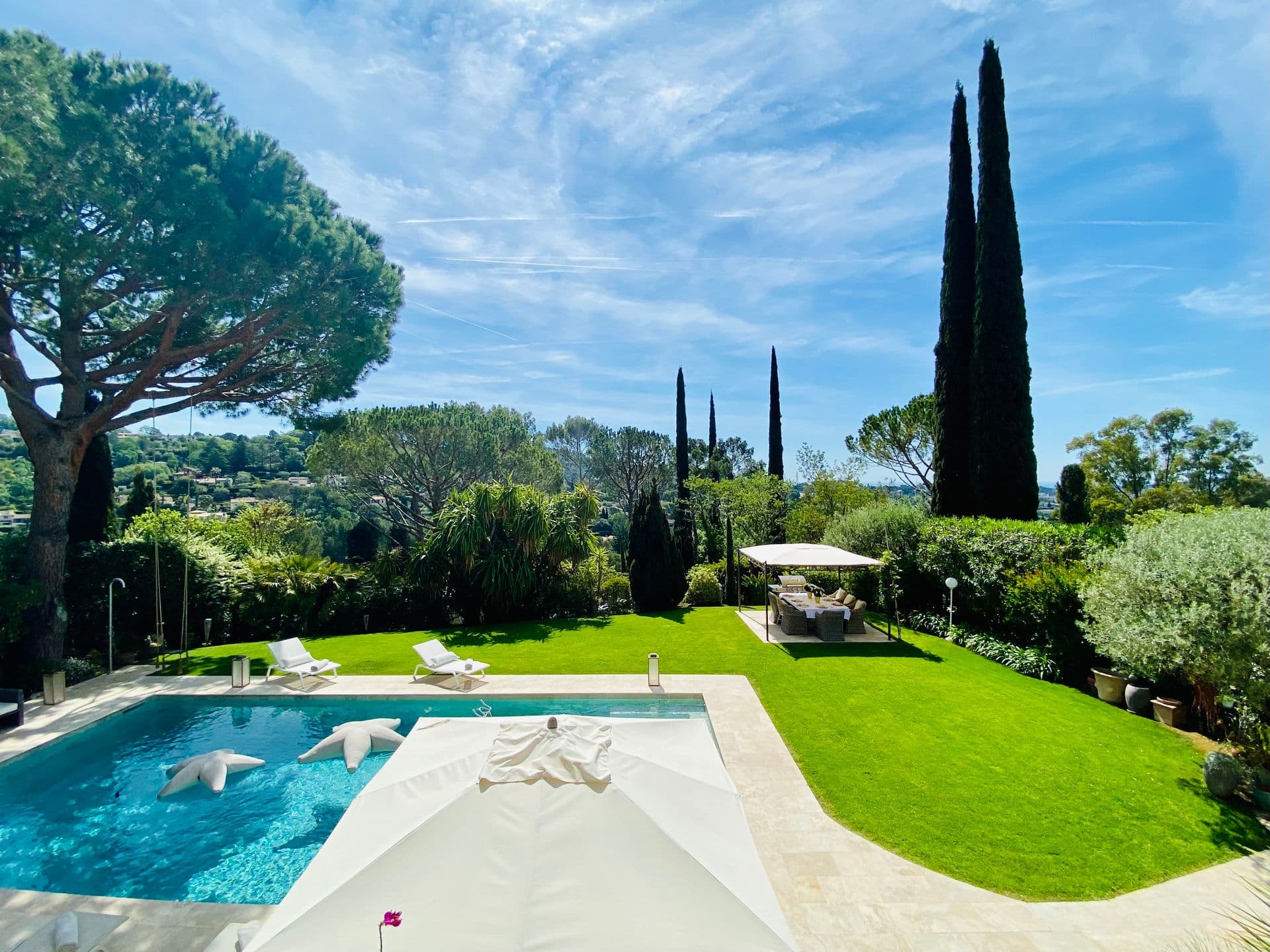 Pool and sun loungers set beside an expansive lawn.
