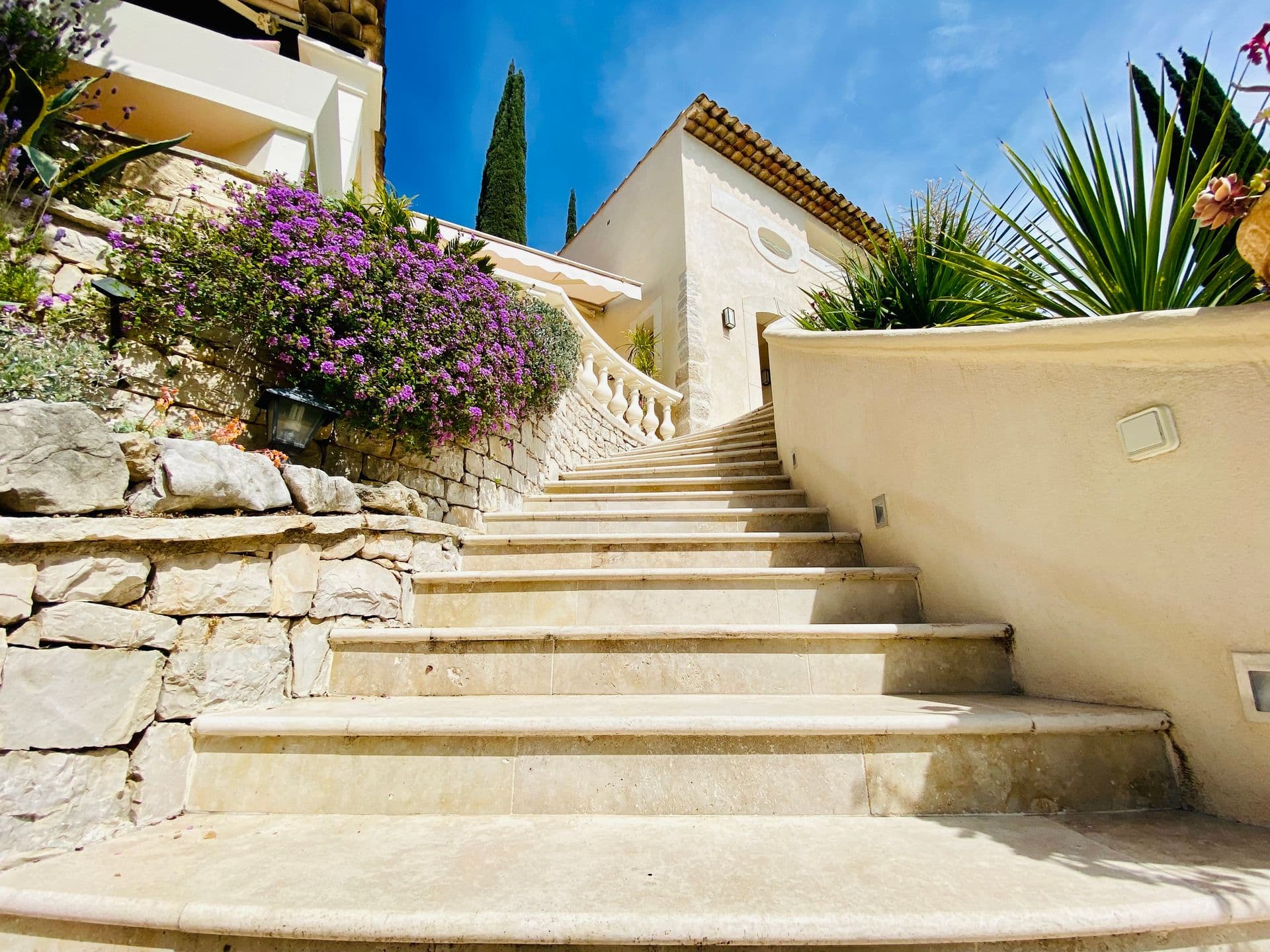 Stone staircase bordered by bougainvillea leading up through the garden.