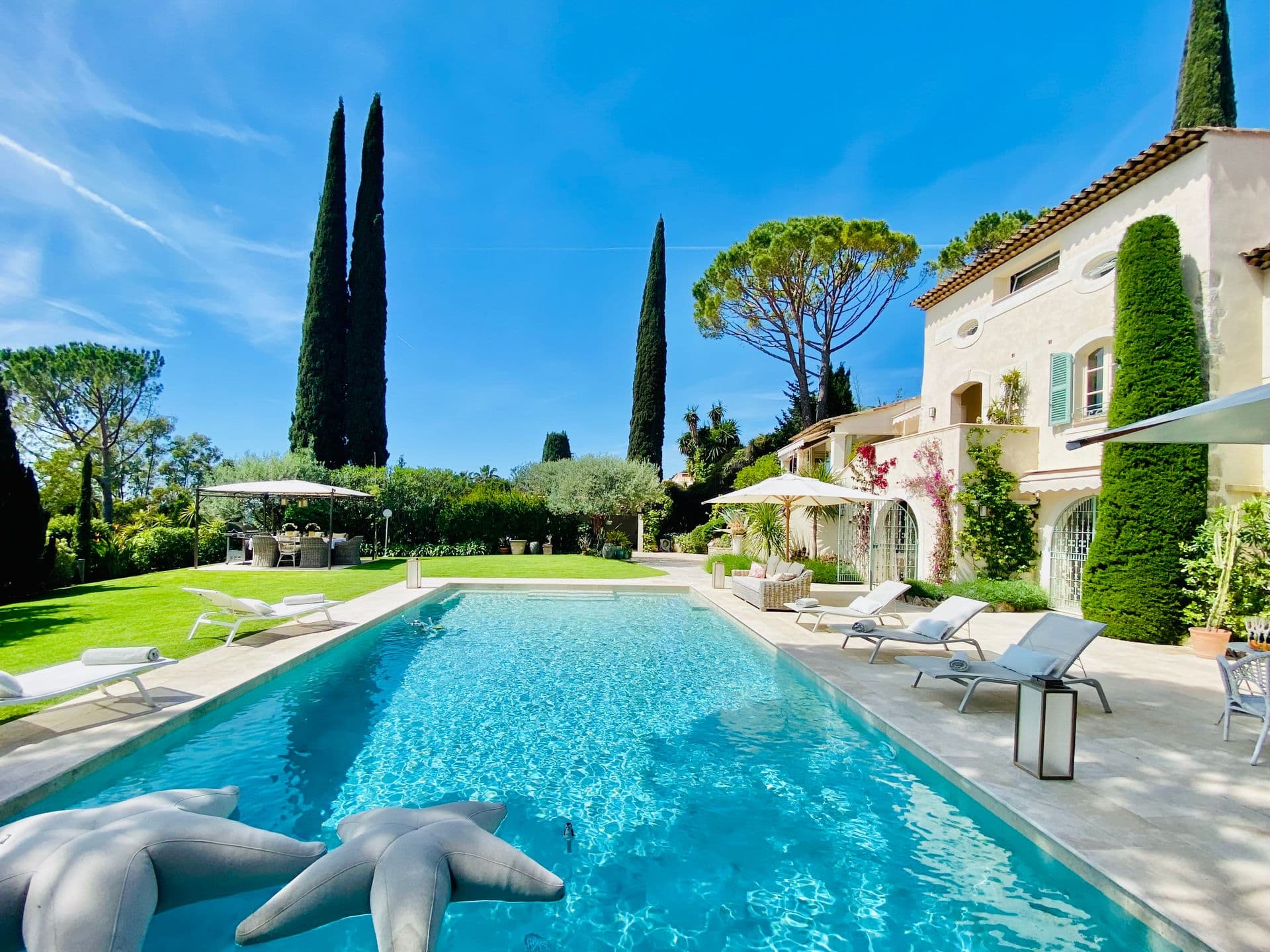 Provencal villa facade with pool, statues and manicured lawn at Orange & Cream, Saint-Tropez.