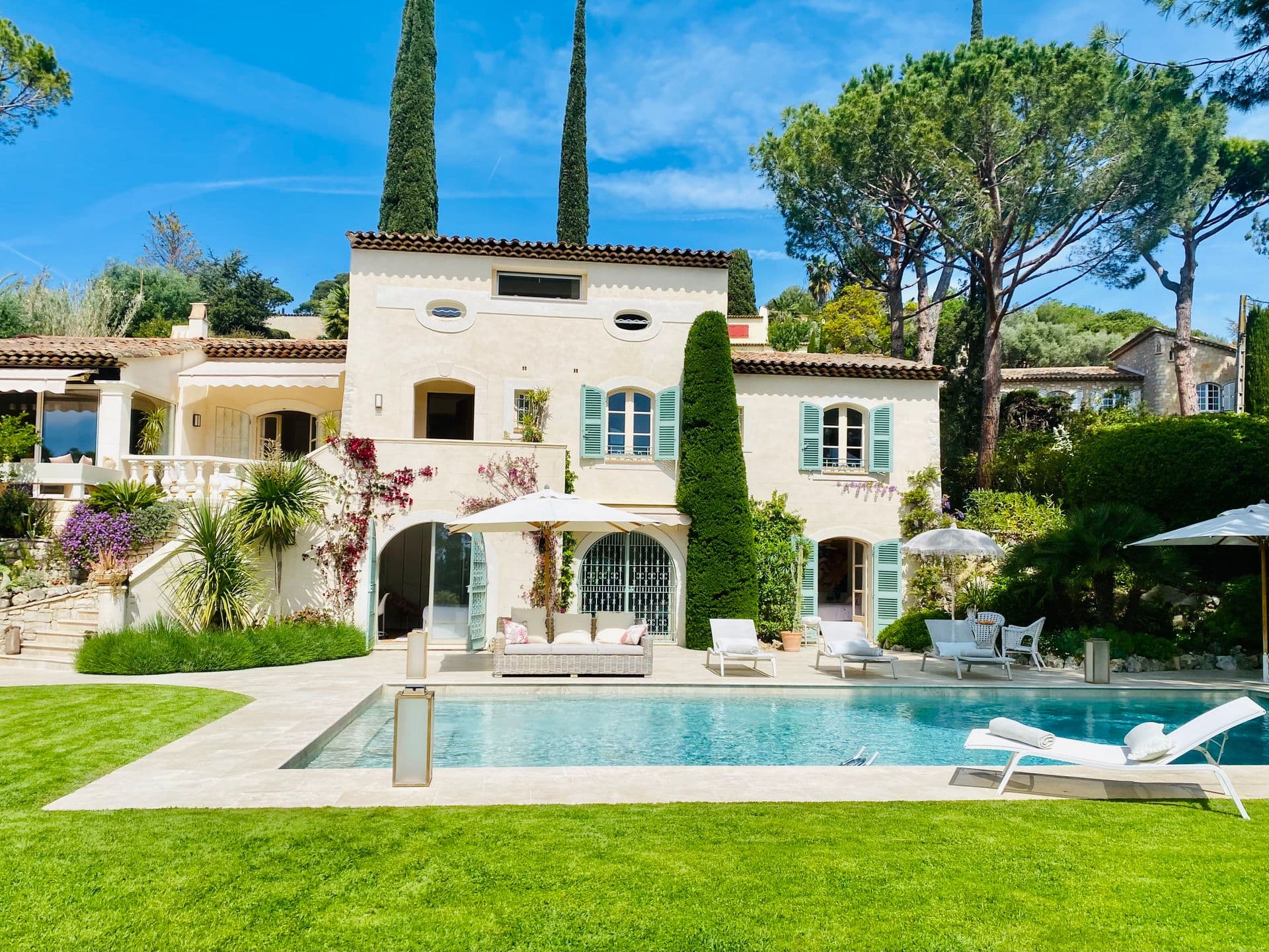 Wide view of the villa and pool framed by cypress and pine trees.