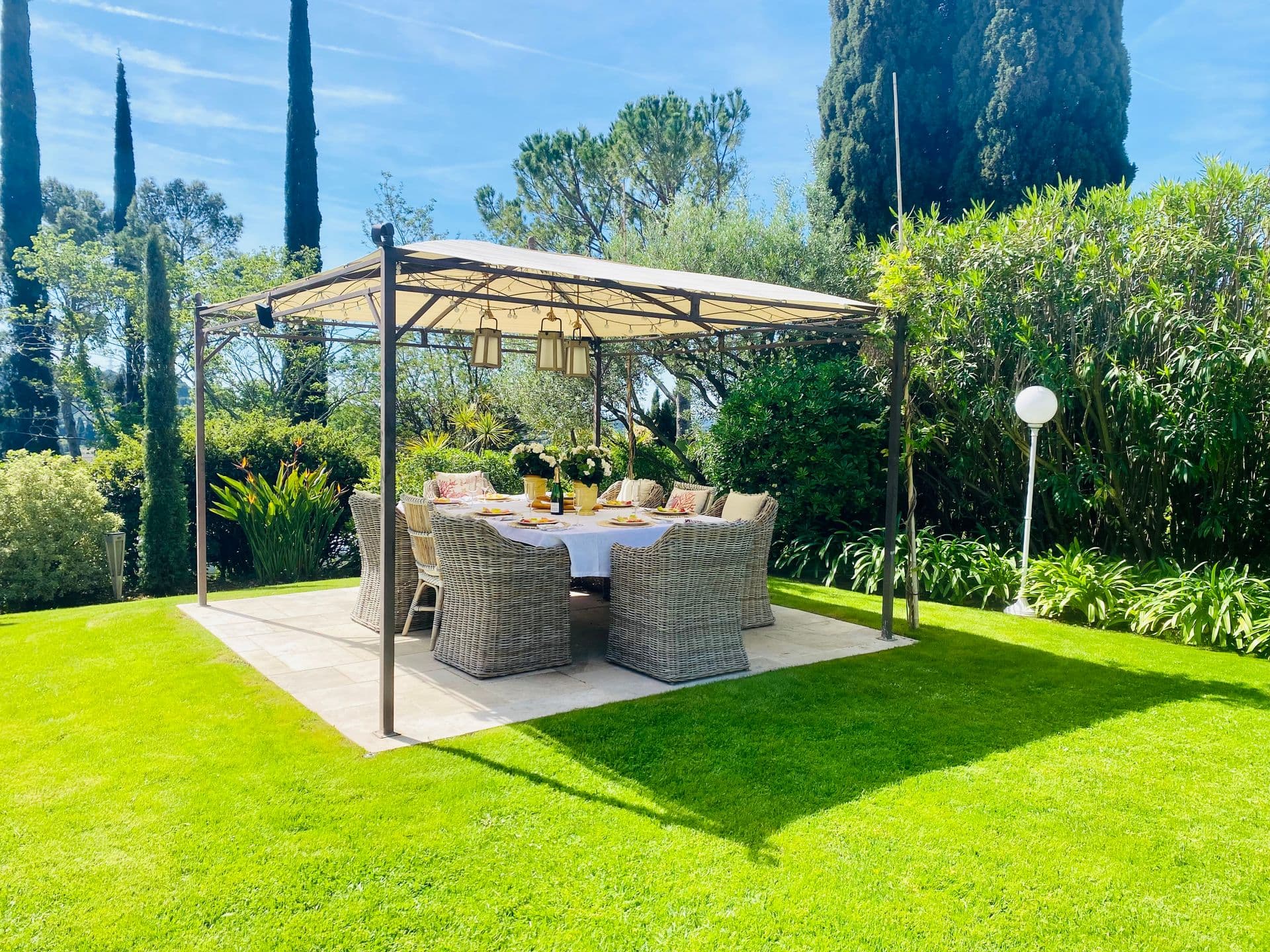 Wrought-iron gazebo with a laid dining table on the lawn.