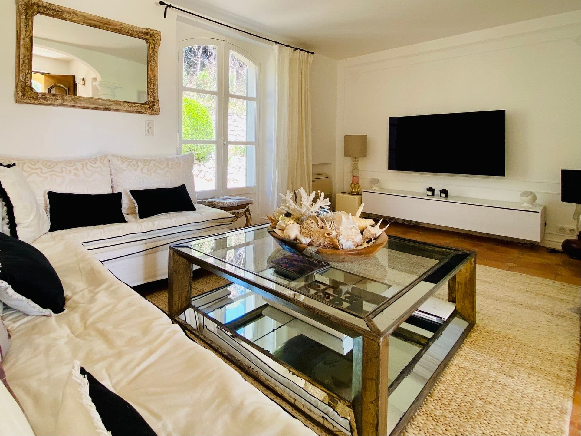 Living room with cream sofas, black cushions and a glass coffee table.