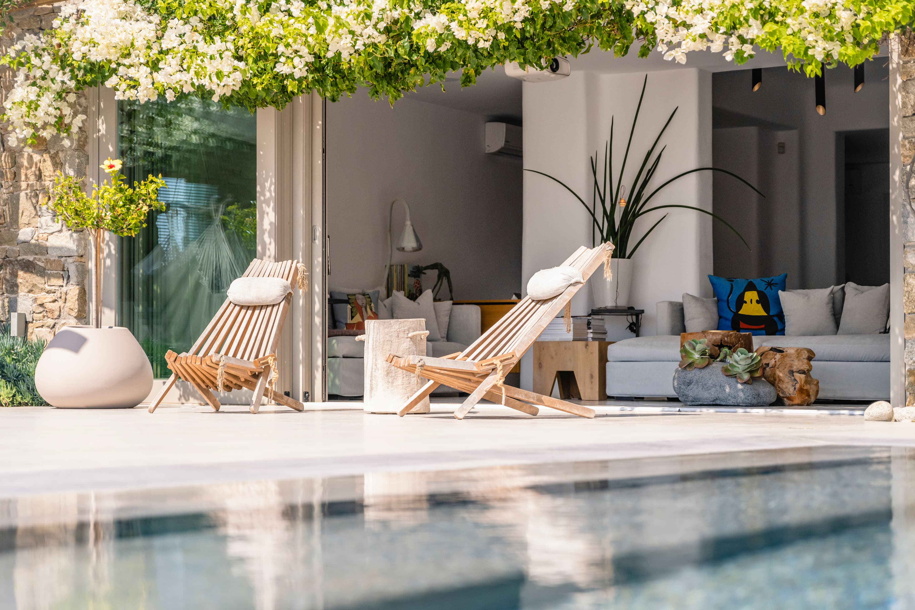 Villa Iliada poolside terrace with teak loungers and white bougainvillea, Mykonos, Greece