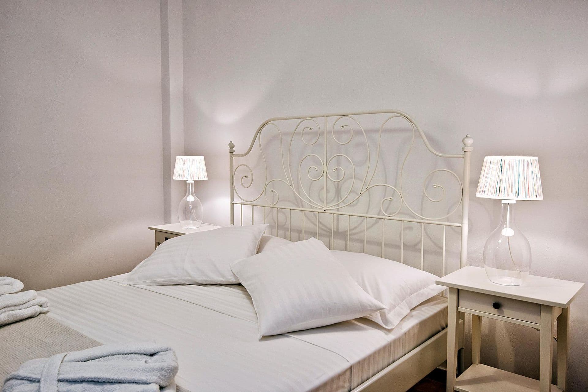 Guest bedroom with stone feature wall and bathrobes laid on the bed at Grecian Gazing