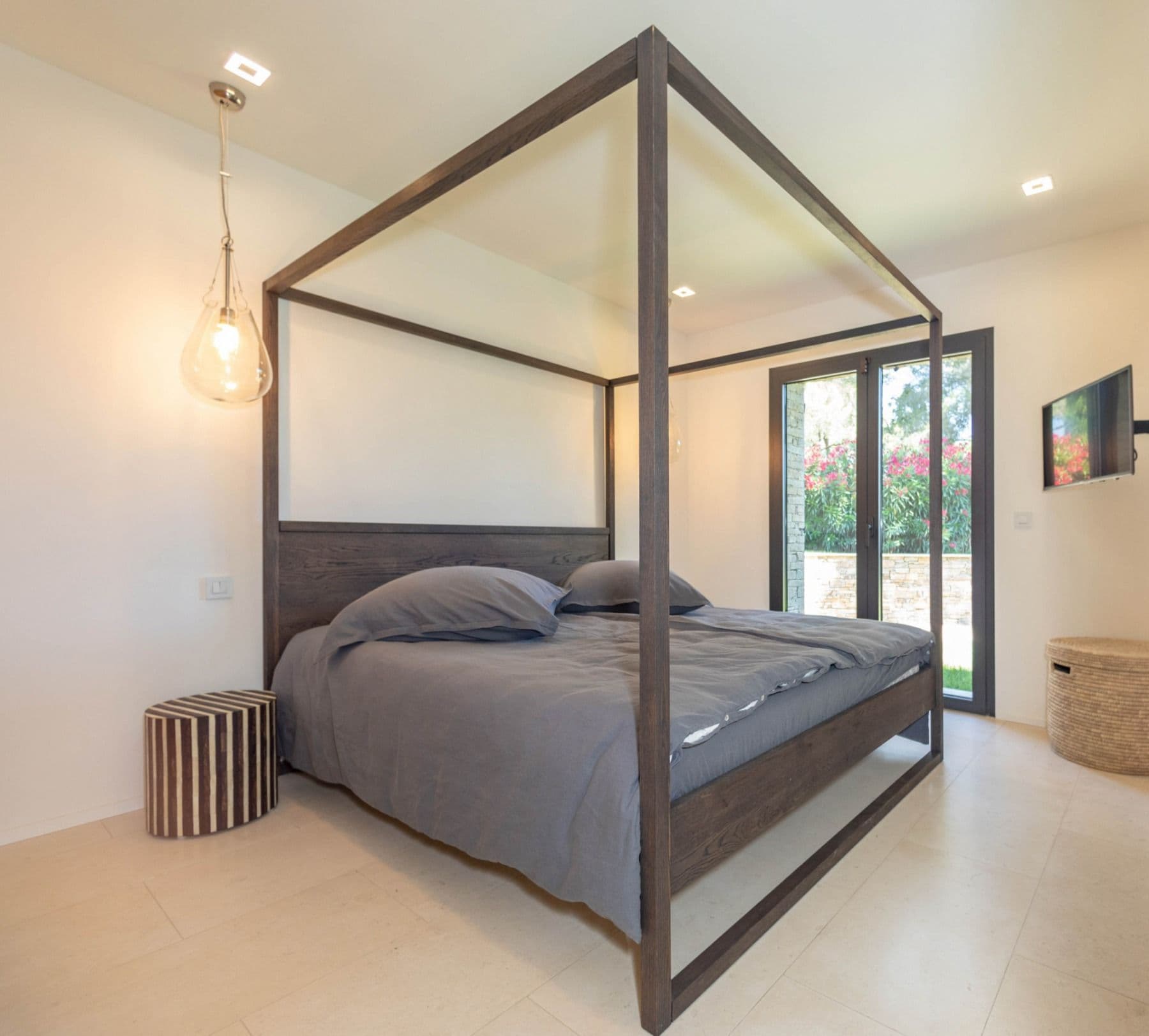 Four-poster bedroom opening through glass doors to the garden at Brilliant Sea, Saint-Tropez