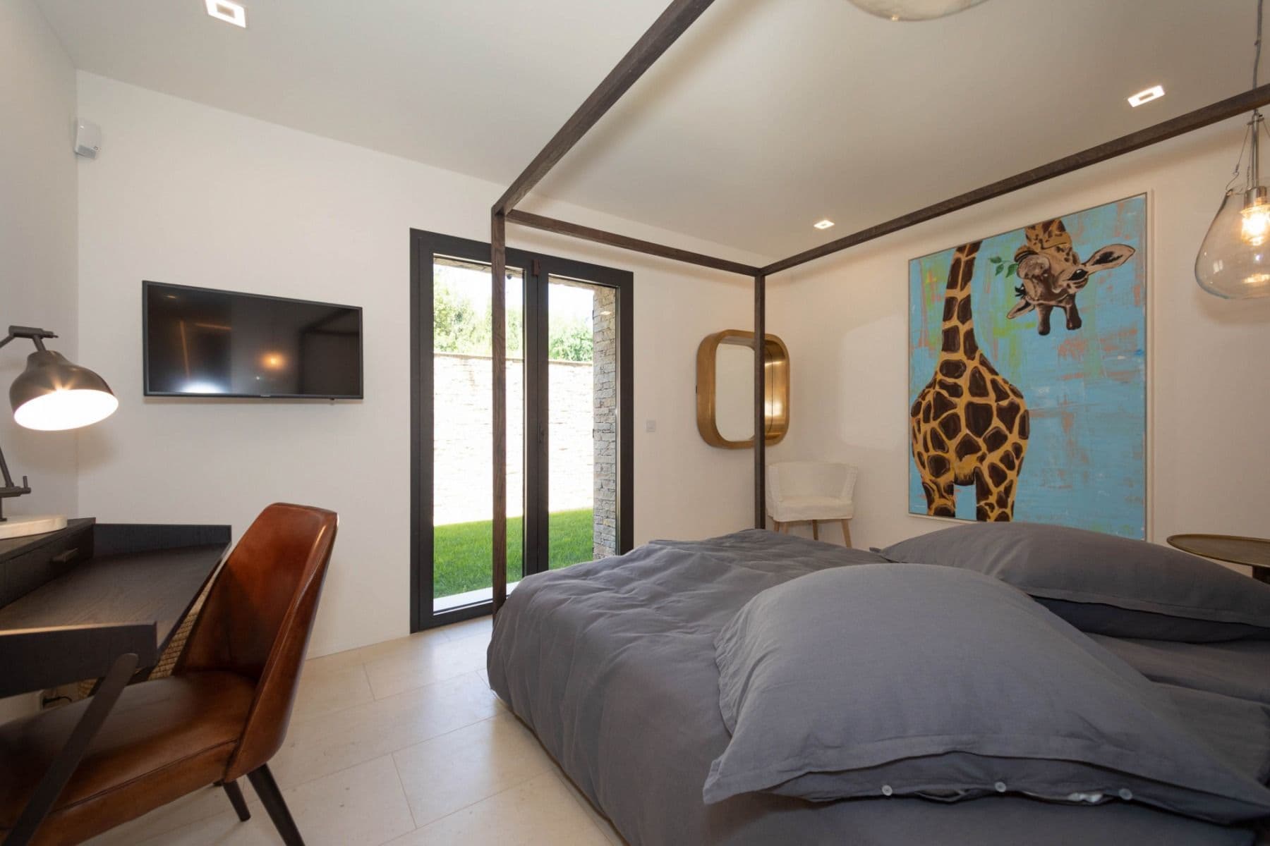 Double bedroom with a four-poster, desk and playful giraffe artwork at Brilliant Sea, Saint-Tropez