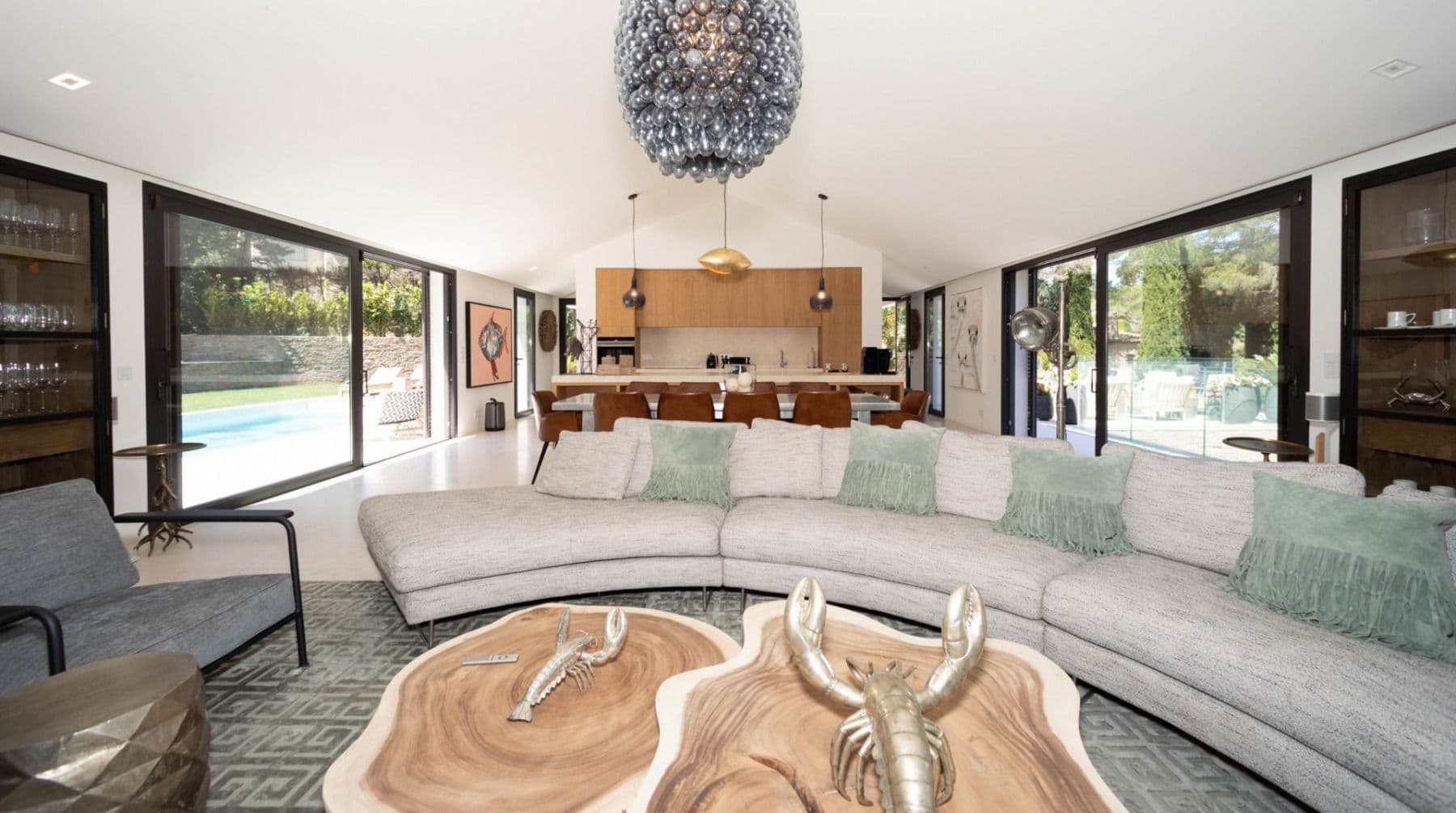 Curved sofa lounge beside the kitchen bar with pool views at Brilliant Sea, Saint-Tropez