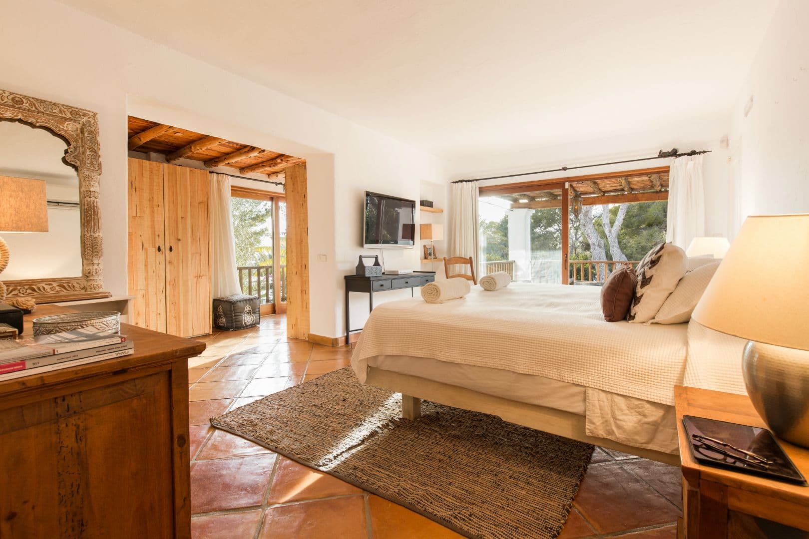Bedroom in warm neutral tones with doors opening to a terrace