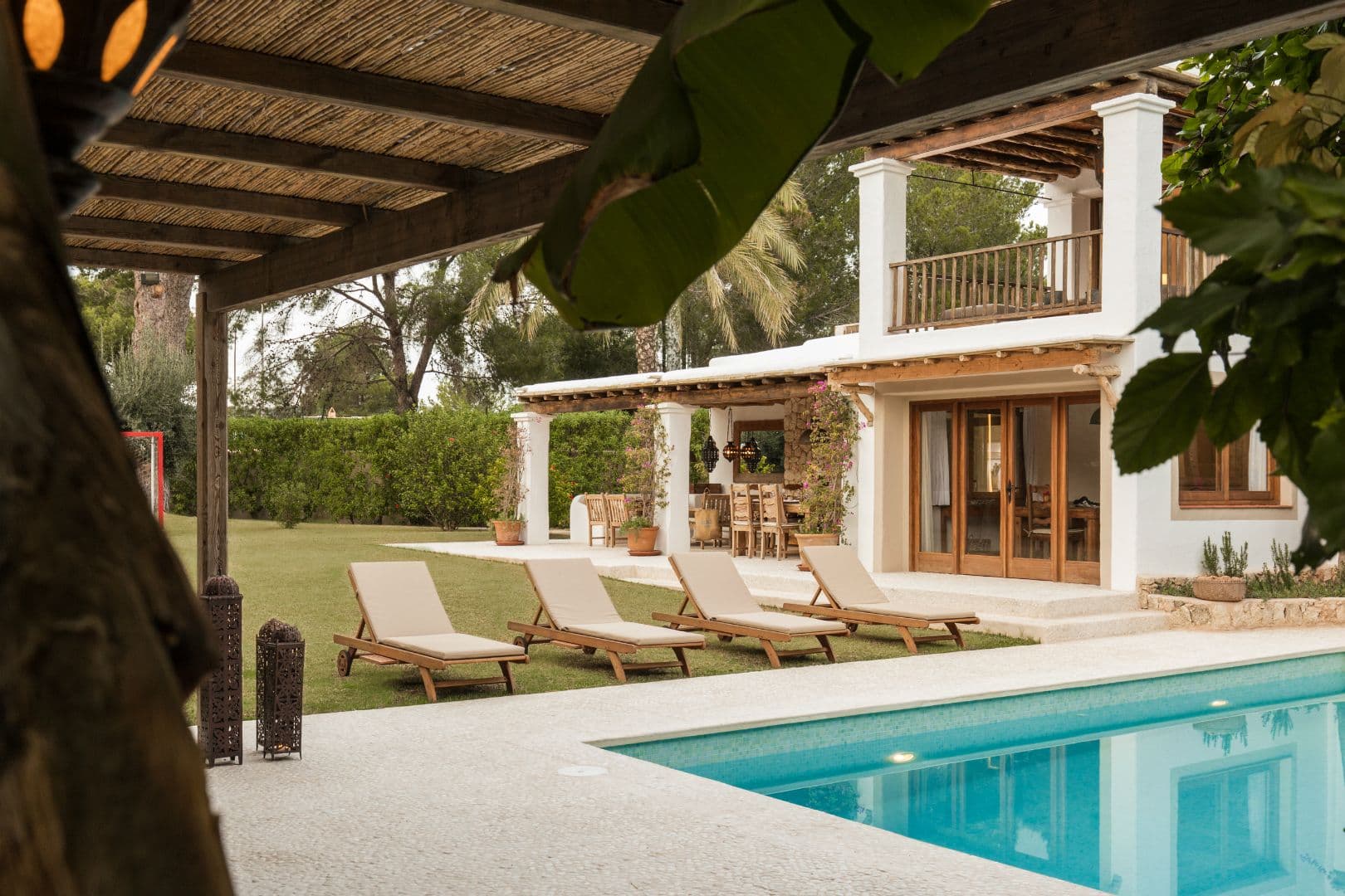 Poolside view framed by a pergola with the villa beyond
