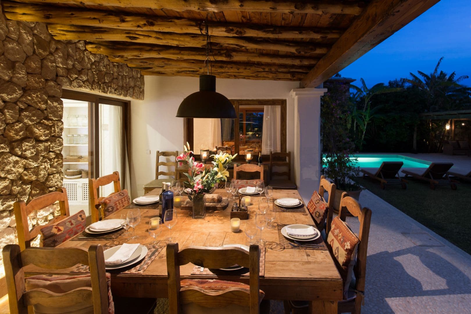 Outdoor dining table set for the evening beside the pool