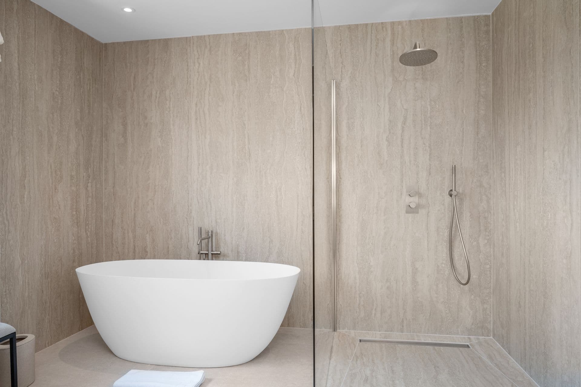 Travertine bathroom with a freestanding tub and walk-in rain shower at Alpilles Retreat, Provence