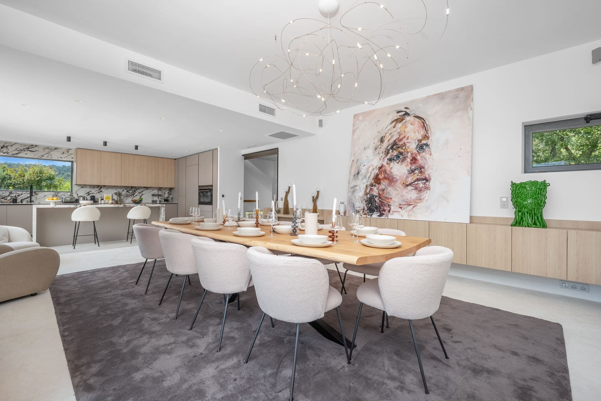 Dining table for eight under a cluster chandelier beside the marble kitchen at Alpilles Retreat