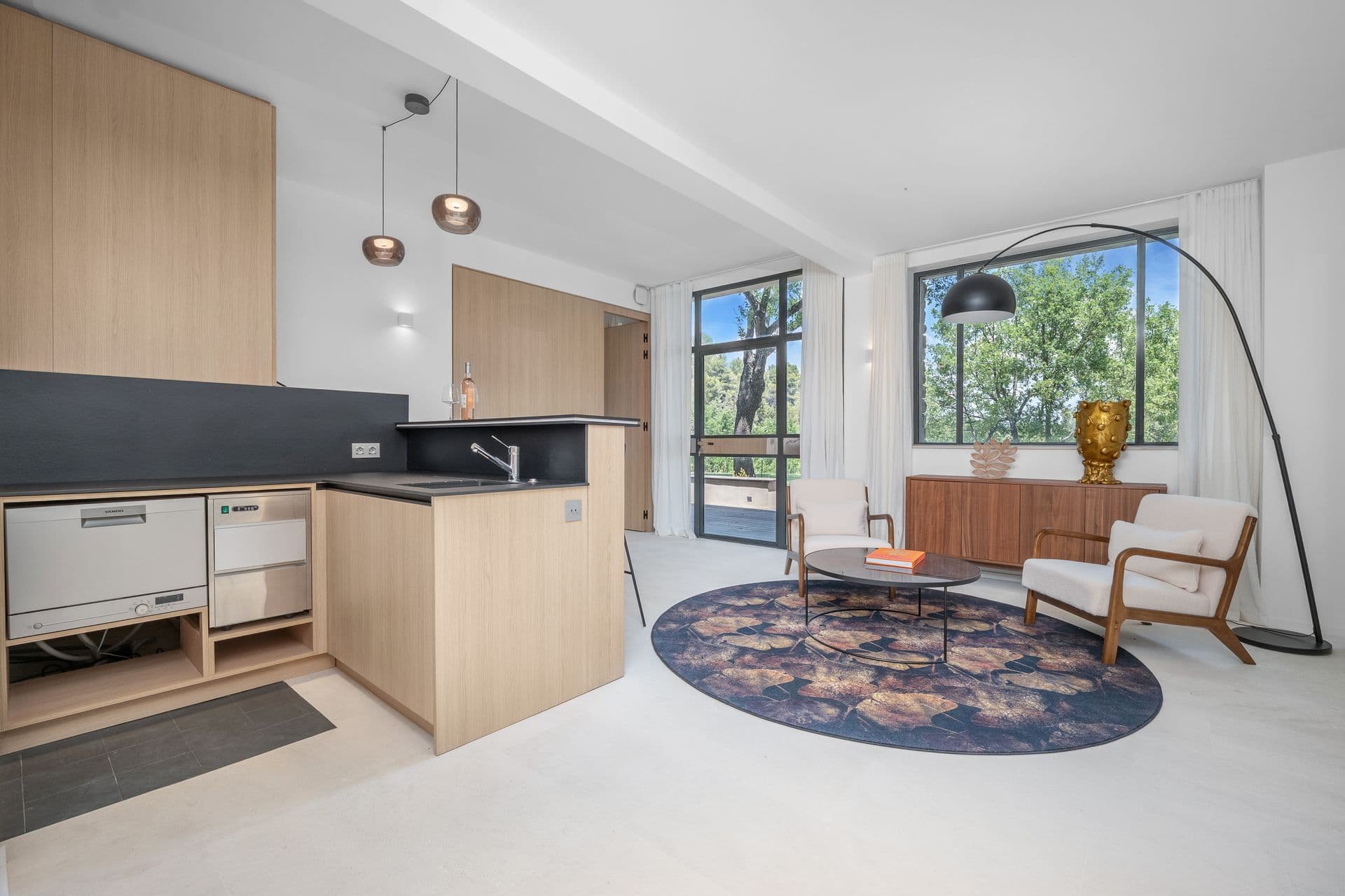 Family room with a kitchenette bar and armchairs on a patterned rug at Alpilles Retreat, Provence