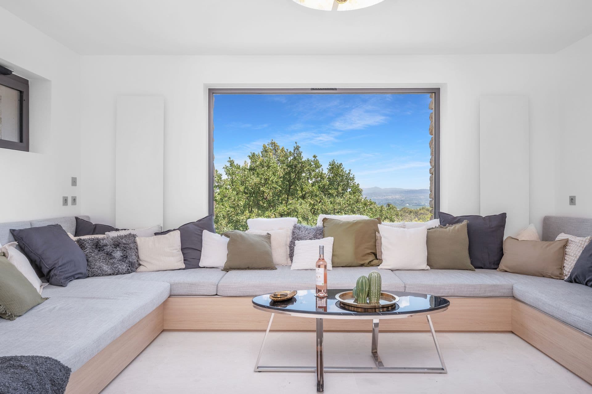 Living room with a large corner sofa framing a picture window over the valley at Alpilles Retreat