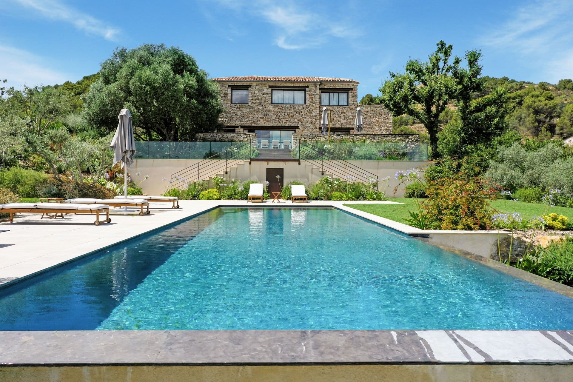 Stone villa above a long infinity pool with sun loungers at Alpilles Retreat, Provence