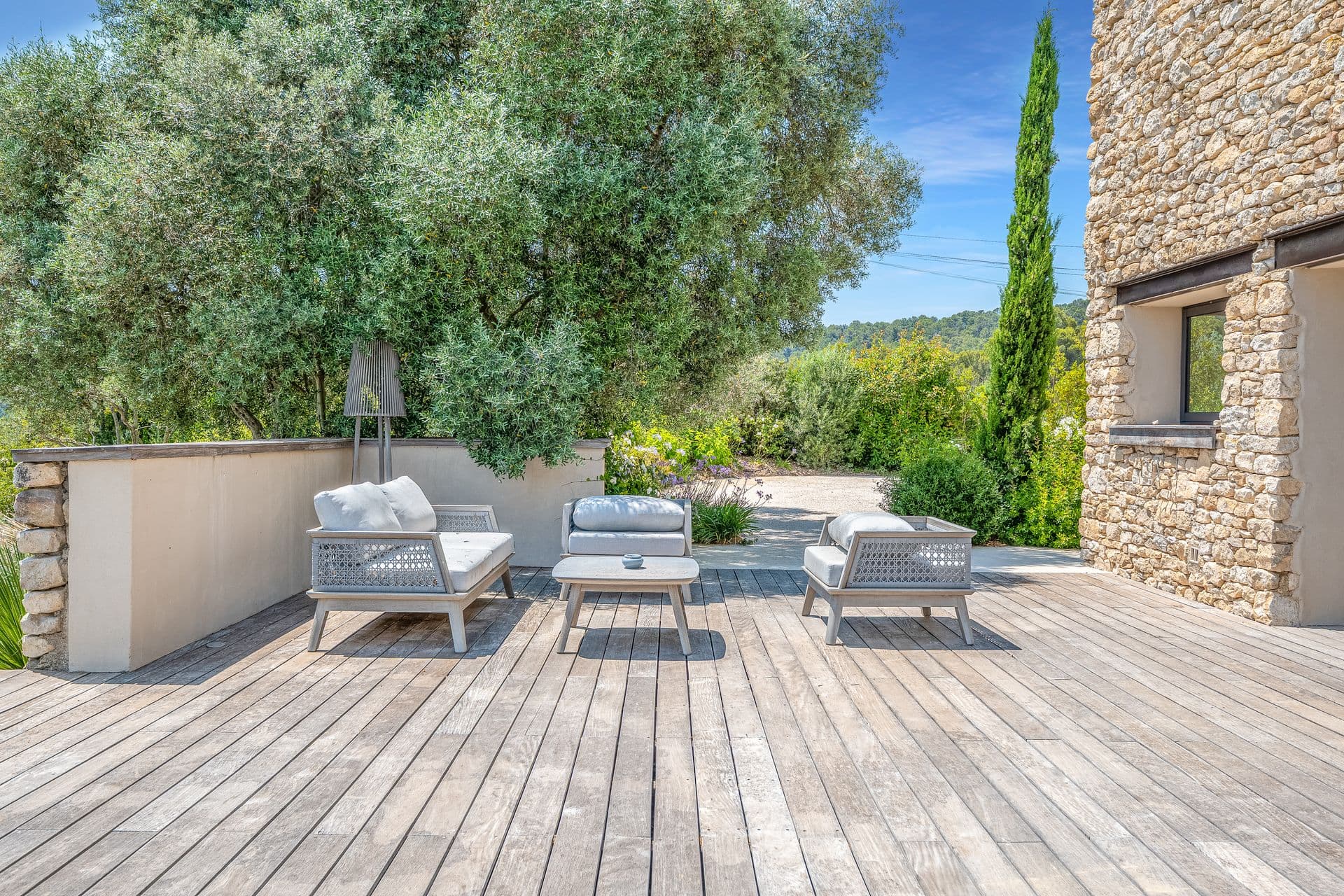 Timber sun deck with loungers beside the stone villa at Alpilles Retreat, Provence