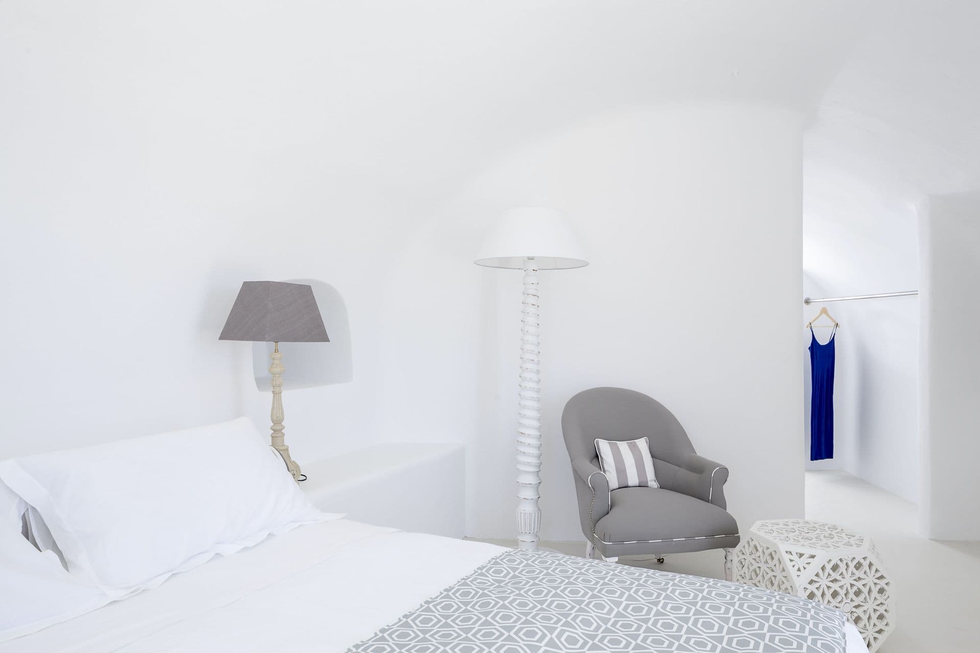 White cave bedroom with a grey armchair and floor lamp at Calypso Dream, Santorini