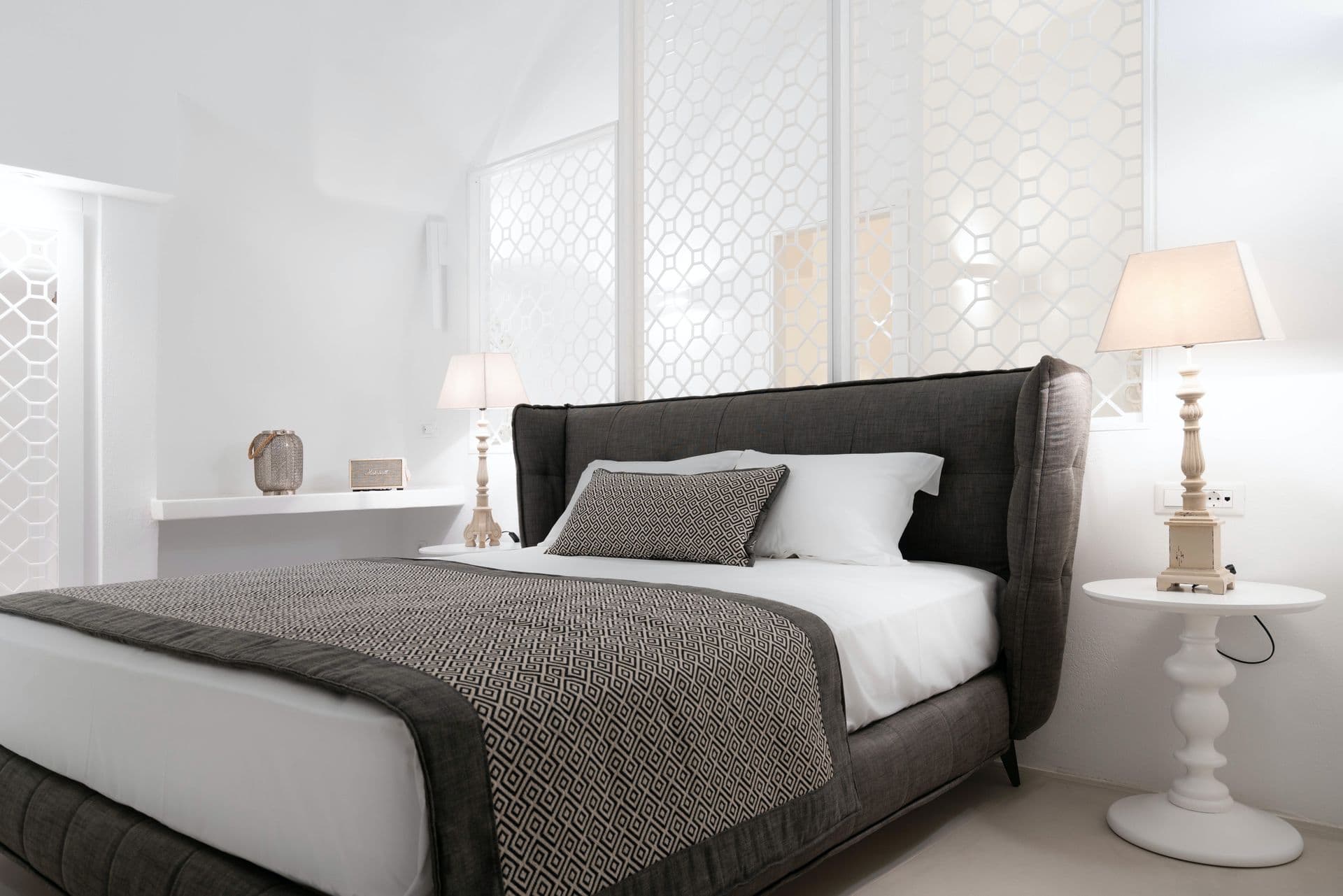 Double bedroom with a grey upholstered headboard and turned-wood lamps at Calypso Dream, Santorini