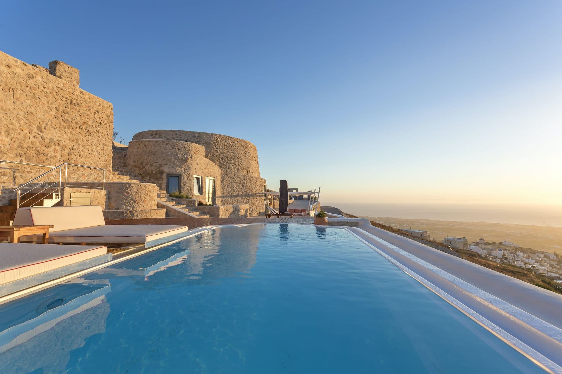 Infinity pool beside a stone cave villa at sunset on Santorini at Calypso Dream, Greece