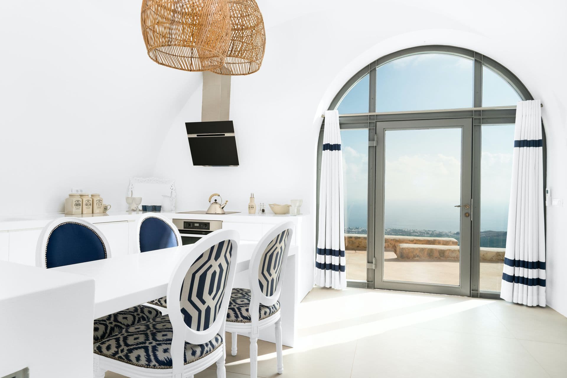 Vaulted white kitchen with an arched door to a sea-view terrace at Calypso Dream, Santorini