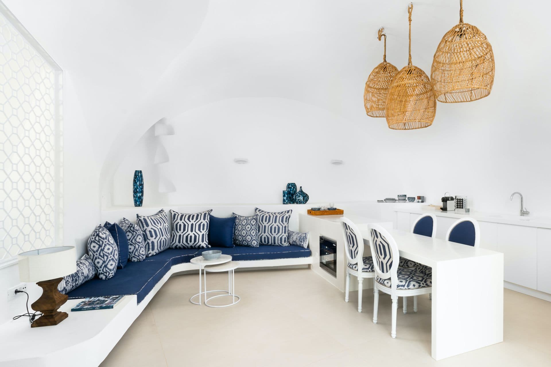 Vaulted cave living room with a built-in blue sofa and dining area at Calypso Dream, Santorini